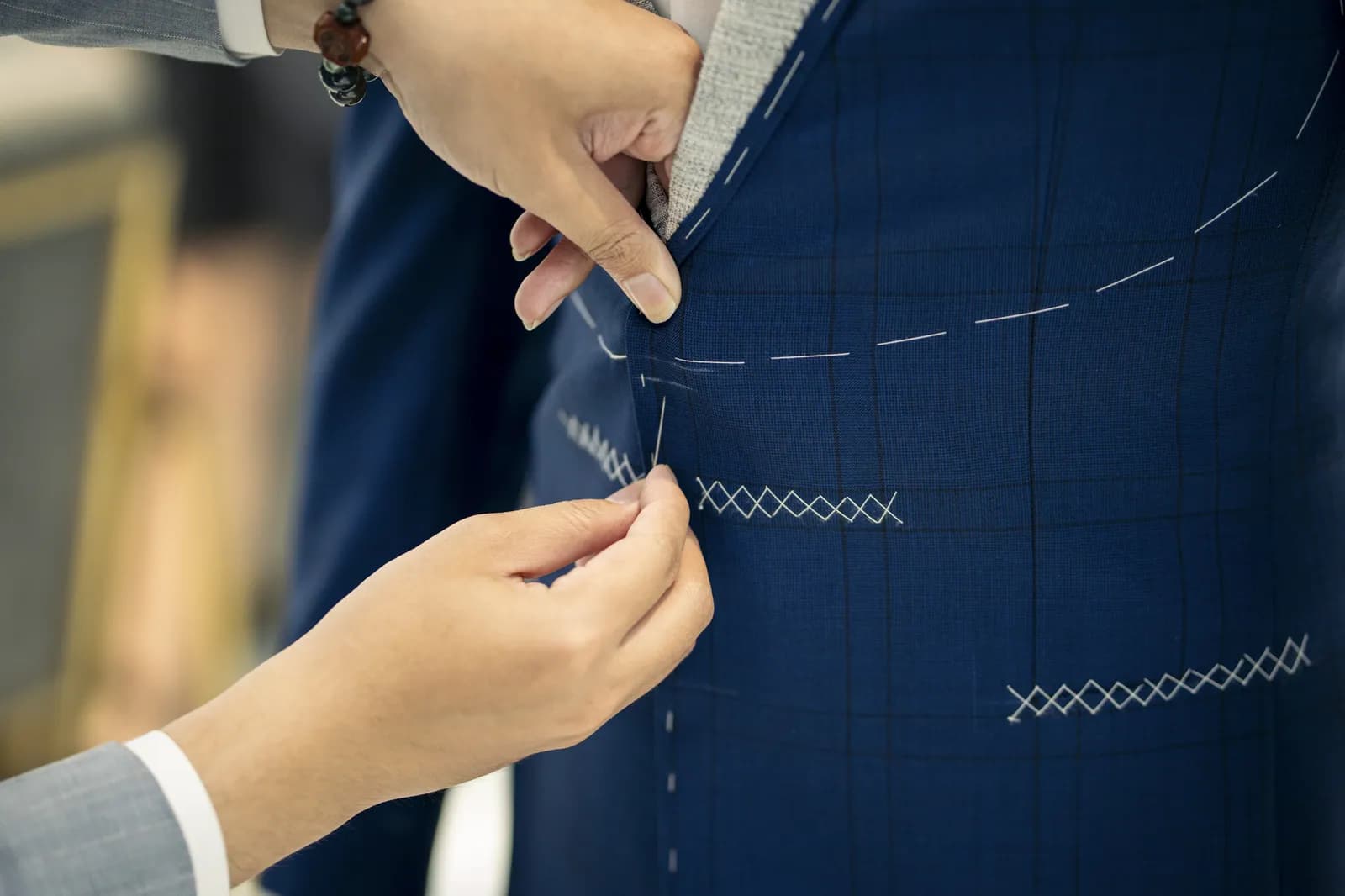 Bàn tay nghệ nhân bên đường lược chữ X trên vải navy