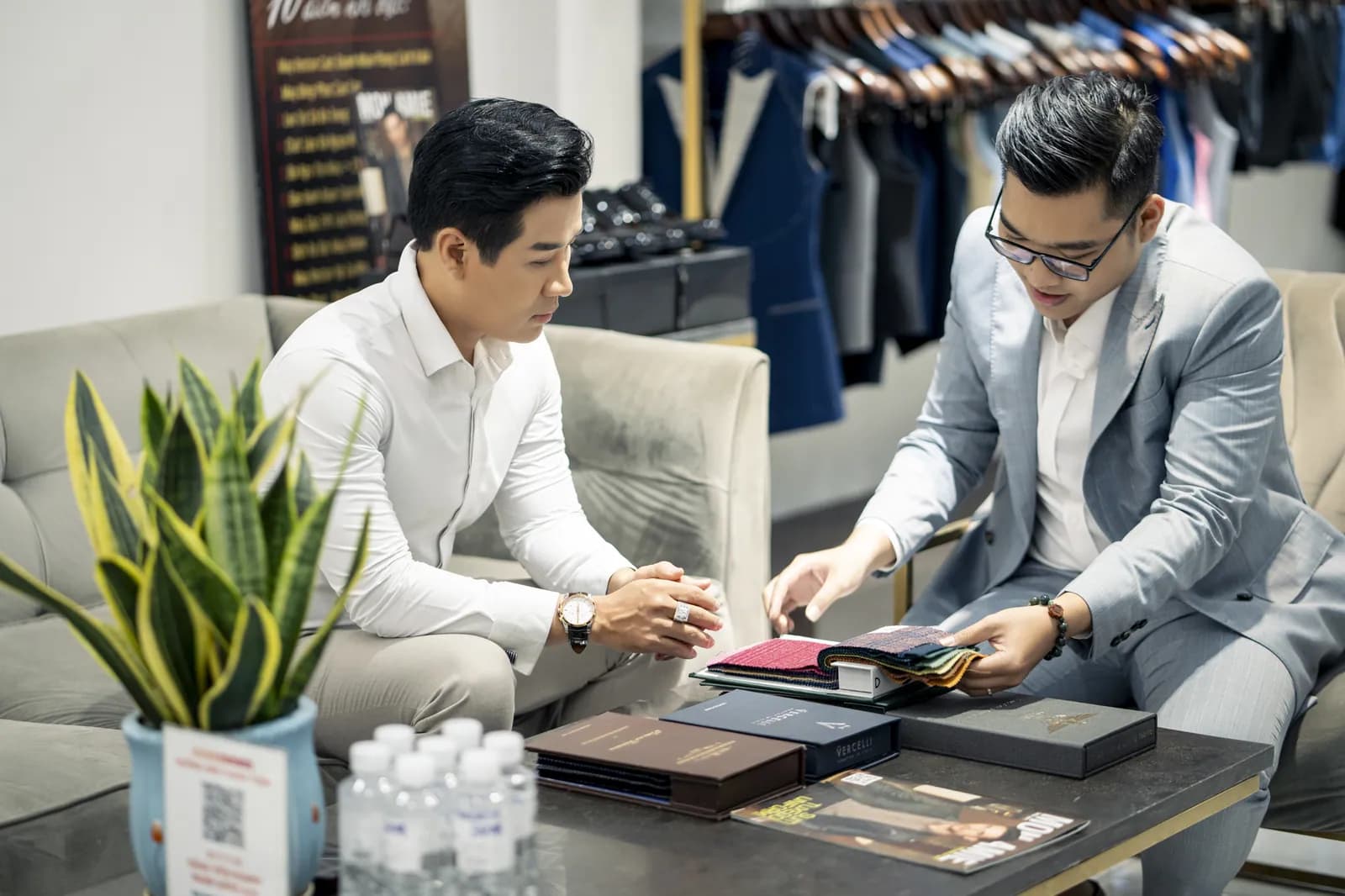 MC Nguyên Khang cùng chuyên viên Mon Amie xem sổ mẫu vải tại showroom