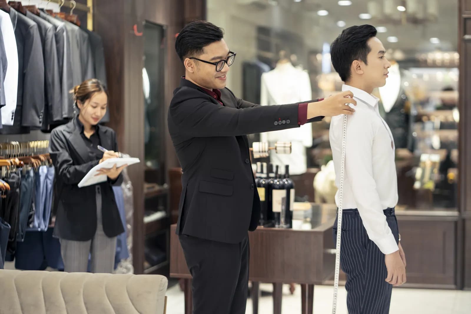 Đo chiều dài tay, trợ lý ghi phiếu số đo
