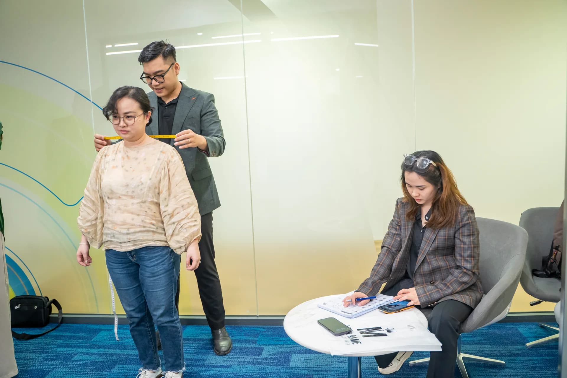 Đo vai cho nhân viên nữ ACBS, đồng nghiệp ghi phiếu số đo bên cạnh