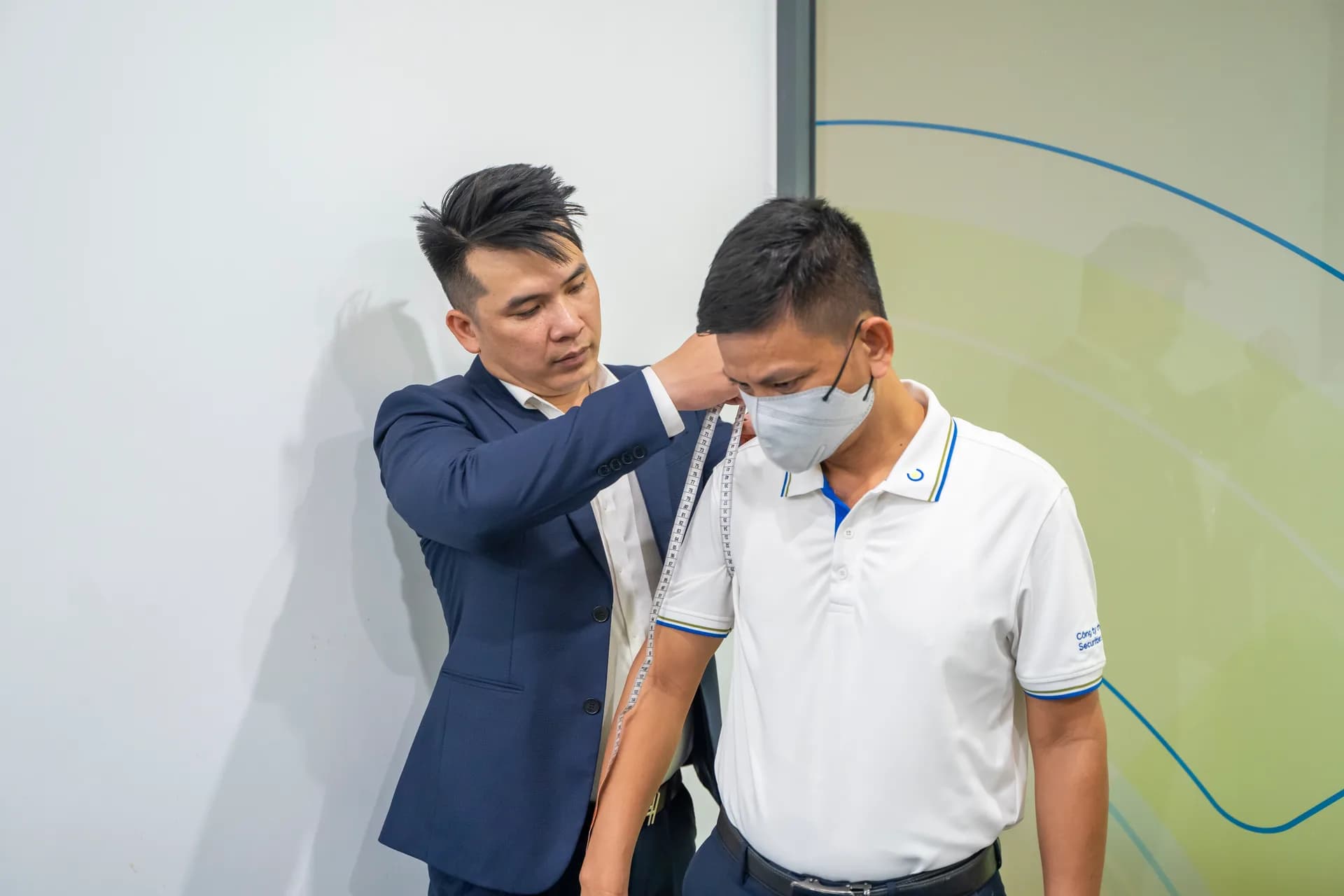 Đo vai cho anh nhân viên áo polo trắng ACBS, thao tác cẩn thận
