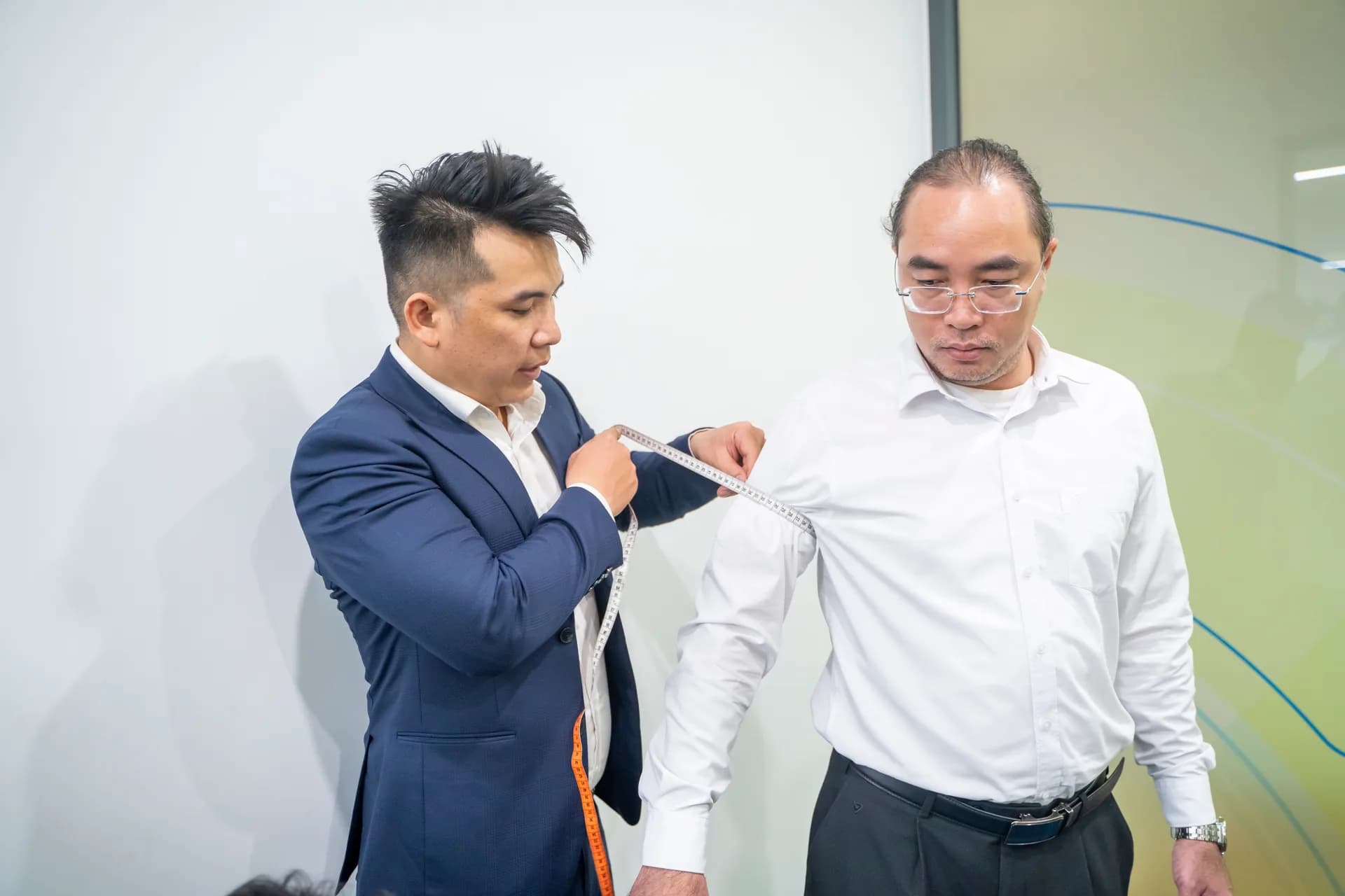 Đo tay áo cho nhân viên nam áo sơ mi trắng, kiểm tra kỹ từng số đo
