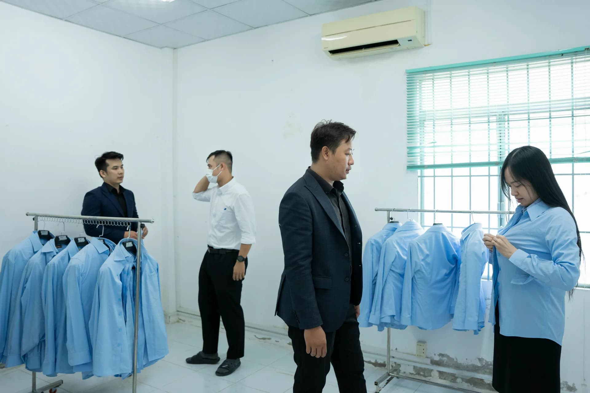Áo sơ mi xanh dương treo sẵn theo size, nhân viên và đội Mon Amie chọn cỡ, minh họa bảng size sơ mi nam