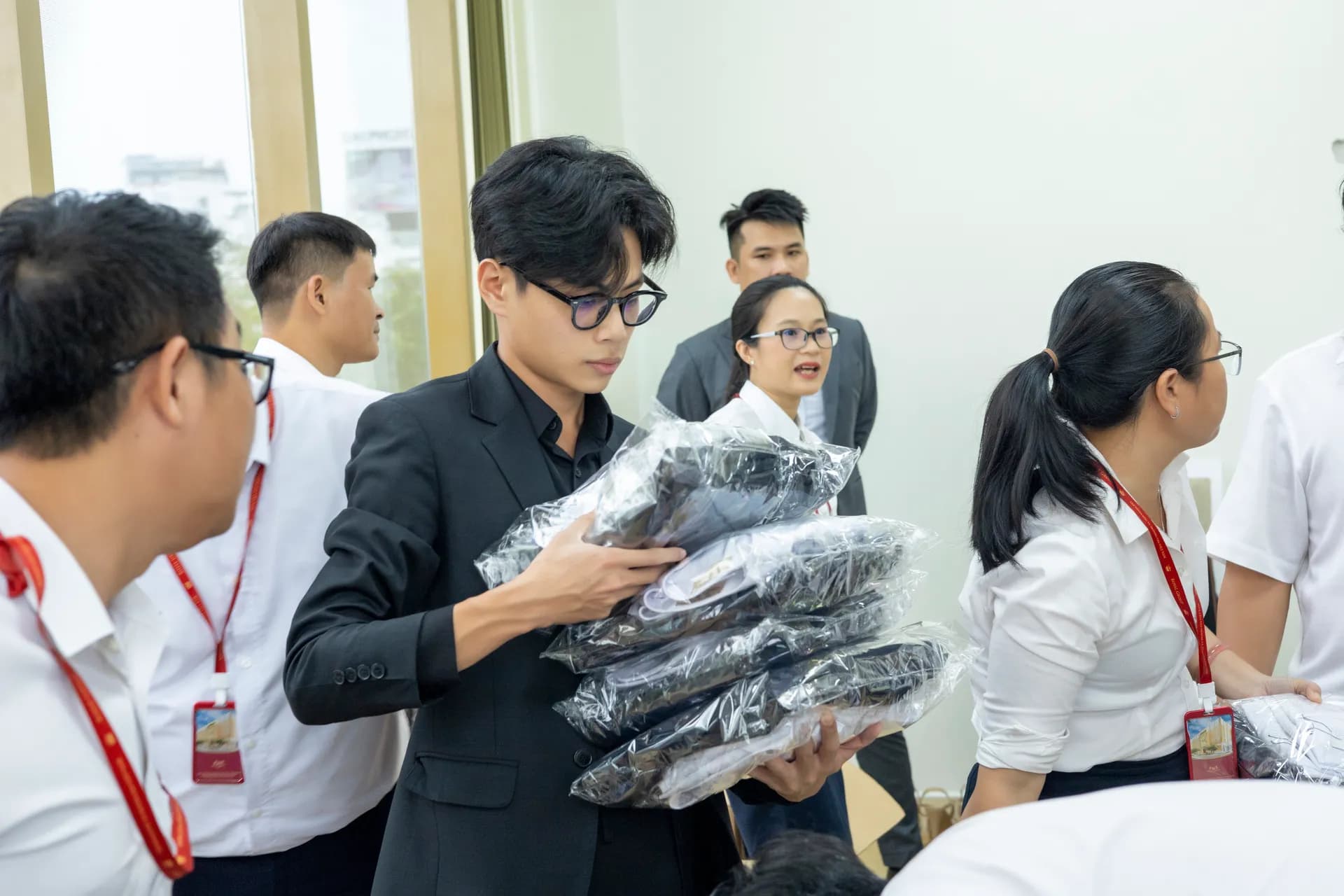 Nhân viên ôm chồng đồng phục đen đóng gói sẵn, phát đồ cho đồng nghiệp