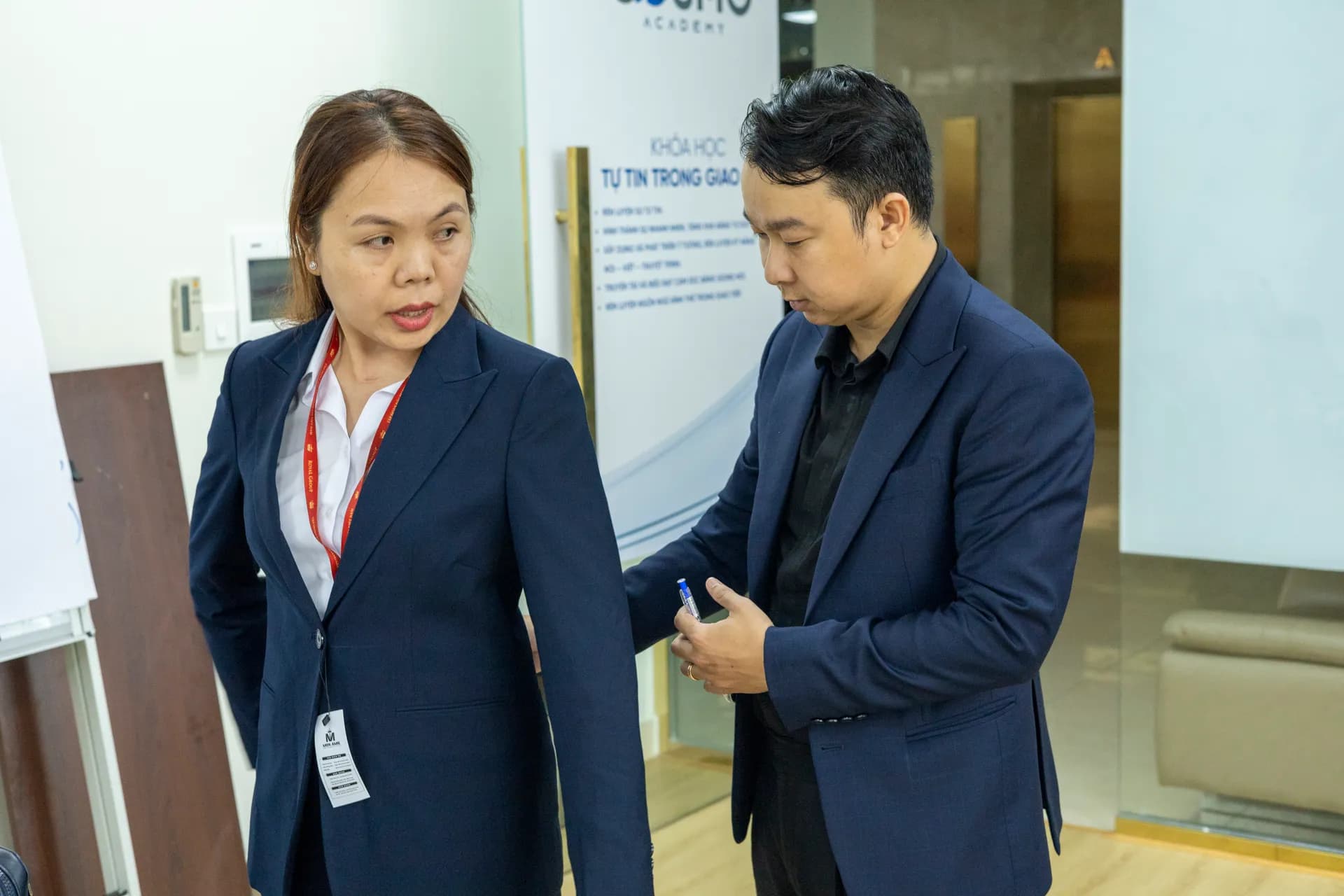 Khách nữ vest navy cổ sơ mi trắng được thợ may chỉnh vai áo, ánh sáng tự nhiên