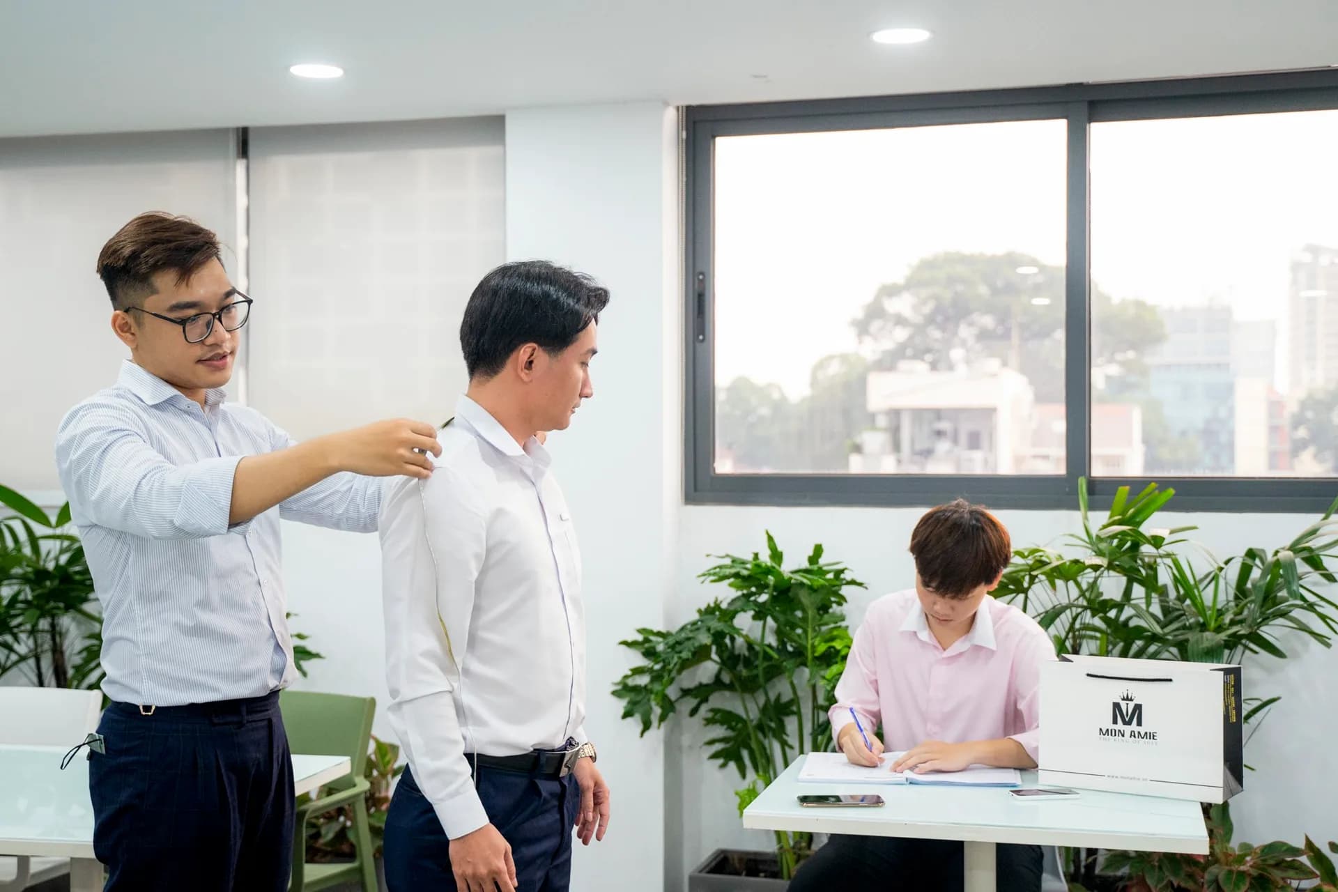 Đo vai cho nhân viên nam bên cửa sổ nhìn ra thành phố