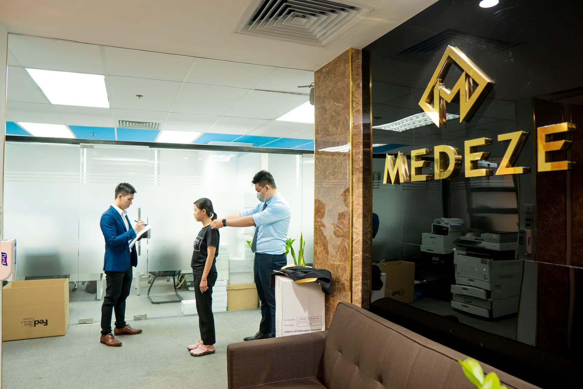 Đo vai cho nhân viên MEDEZE bên bảng hiệu công ty