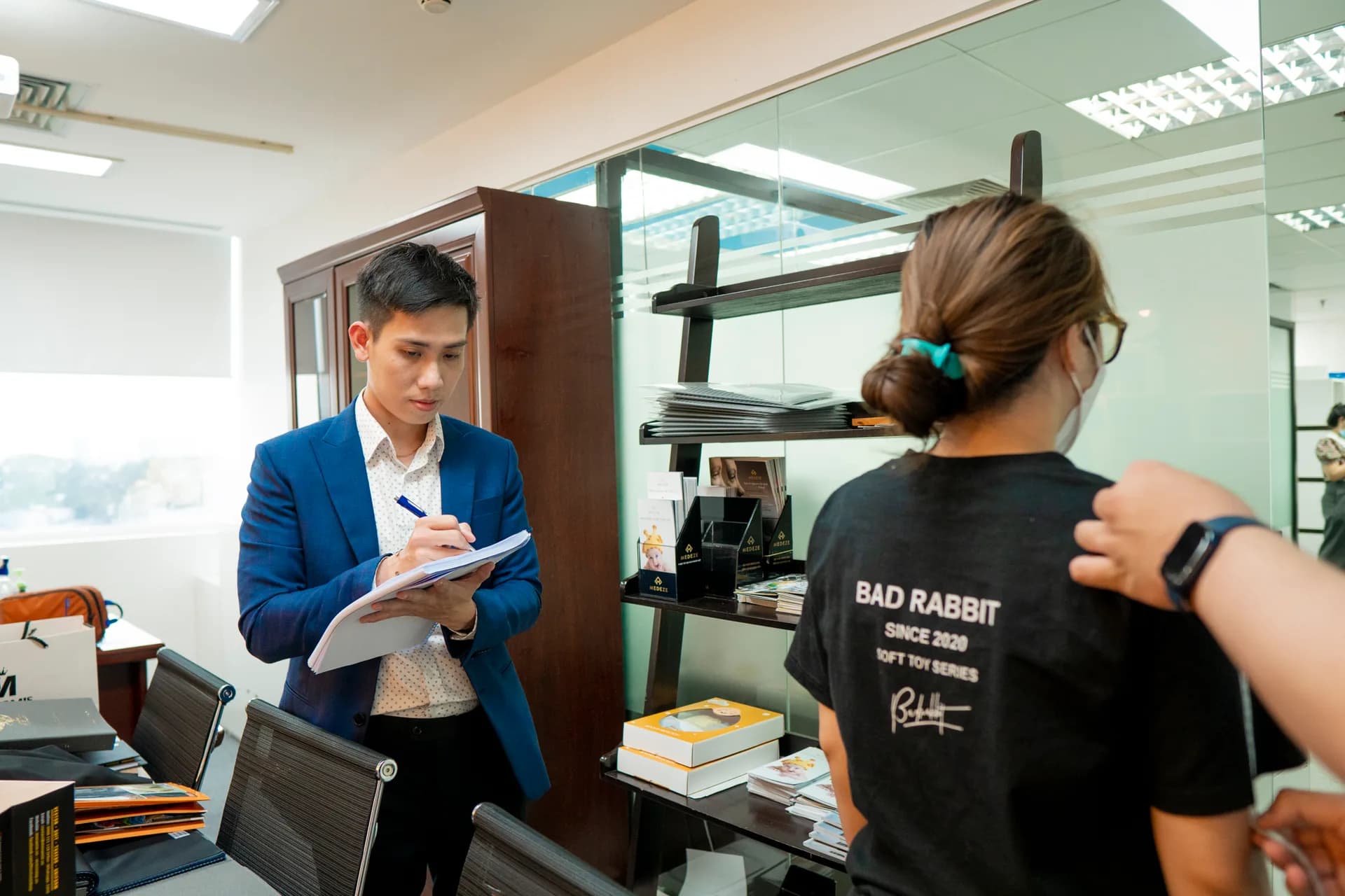 Nhân viên ghi phiếu số đo khi thợ may đo vai