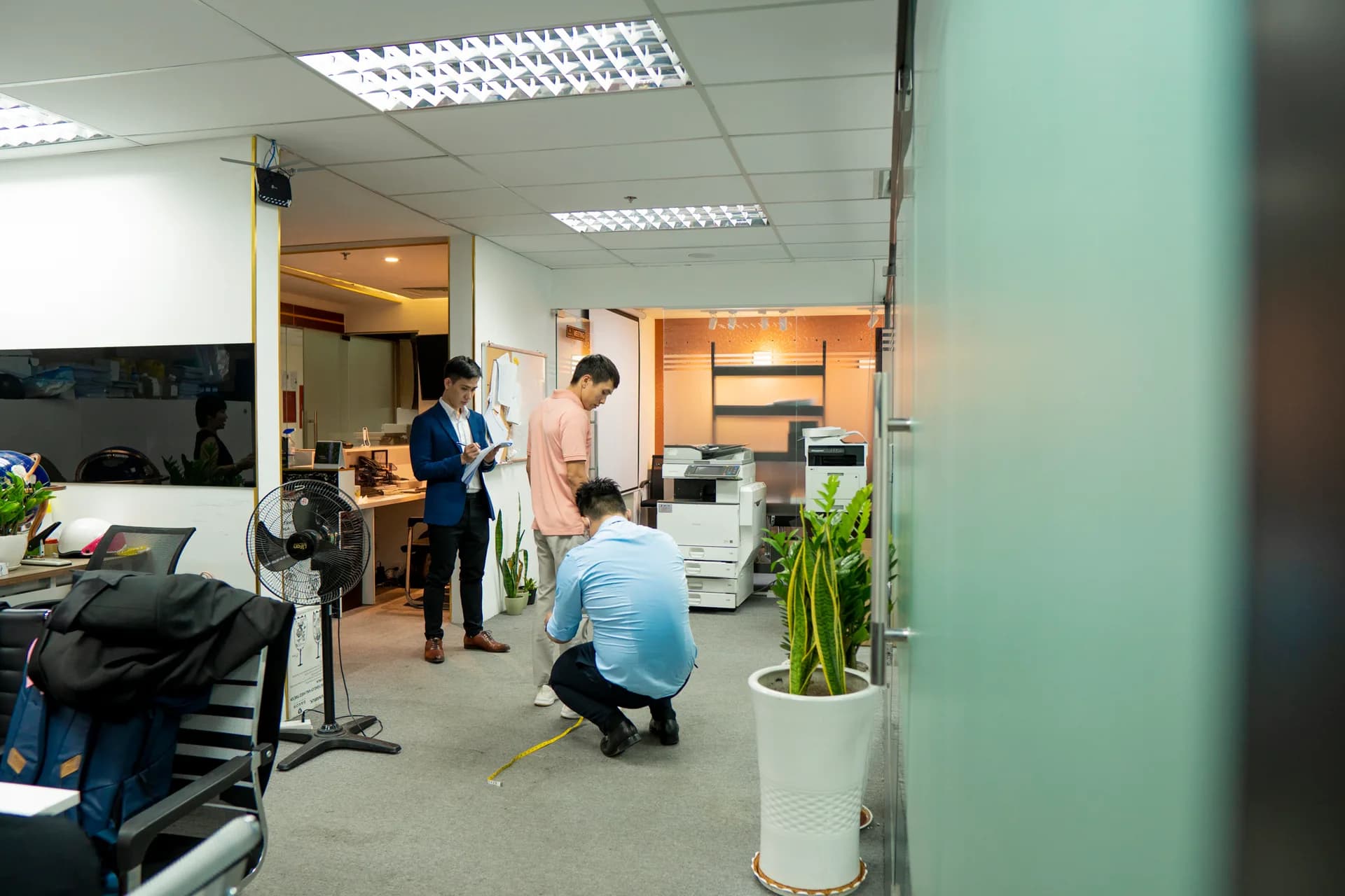 Đo chiều dài quần cho nhân viên nam giữa văn phòng