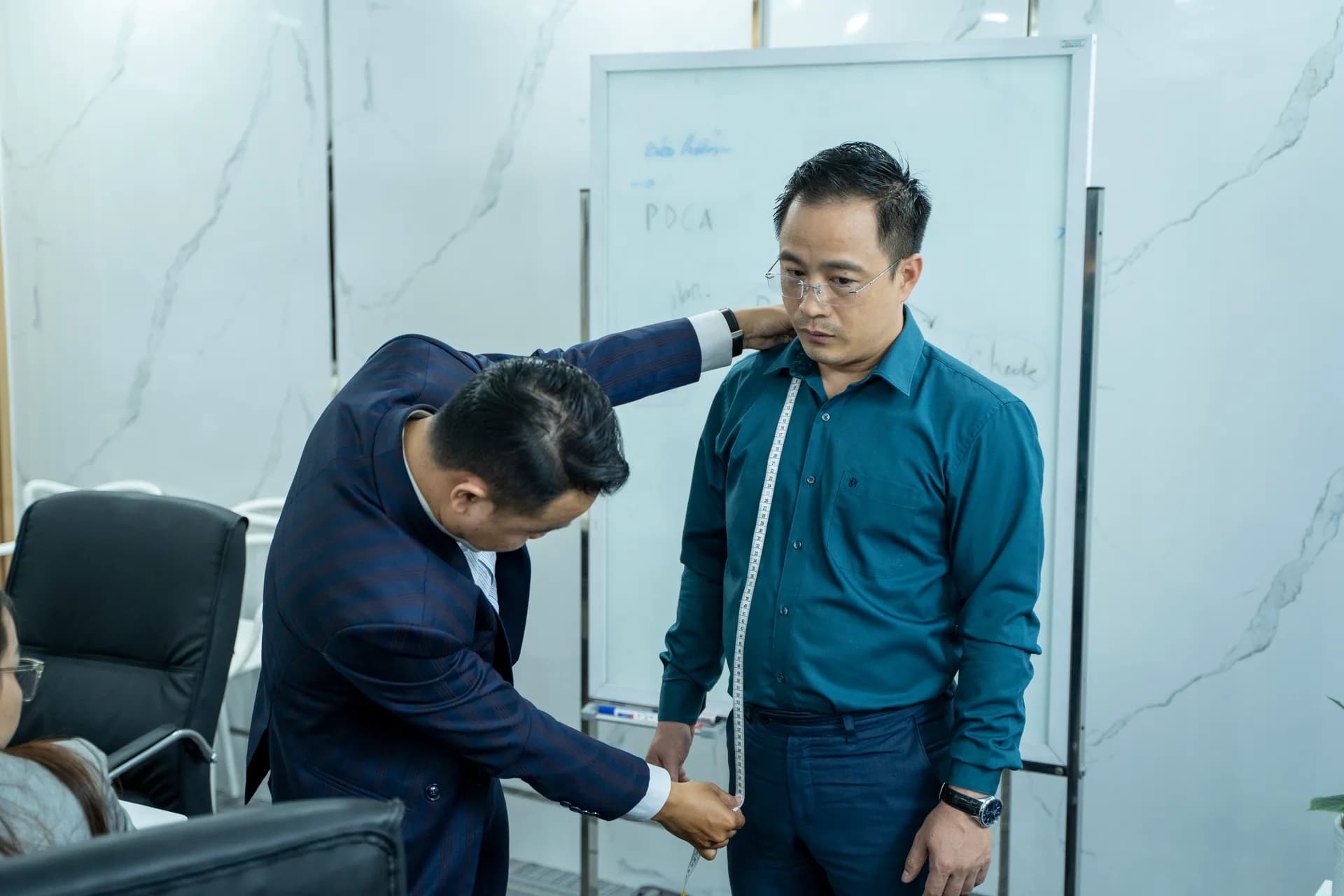 Đo chiều dài thân áo cho nhân viên nam áo sơ mi xanh cổ vịt