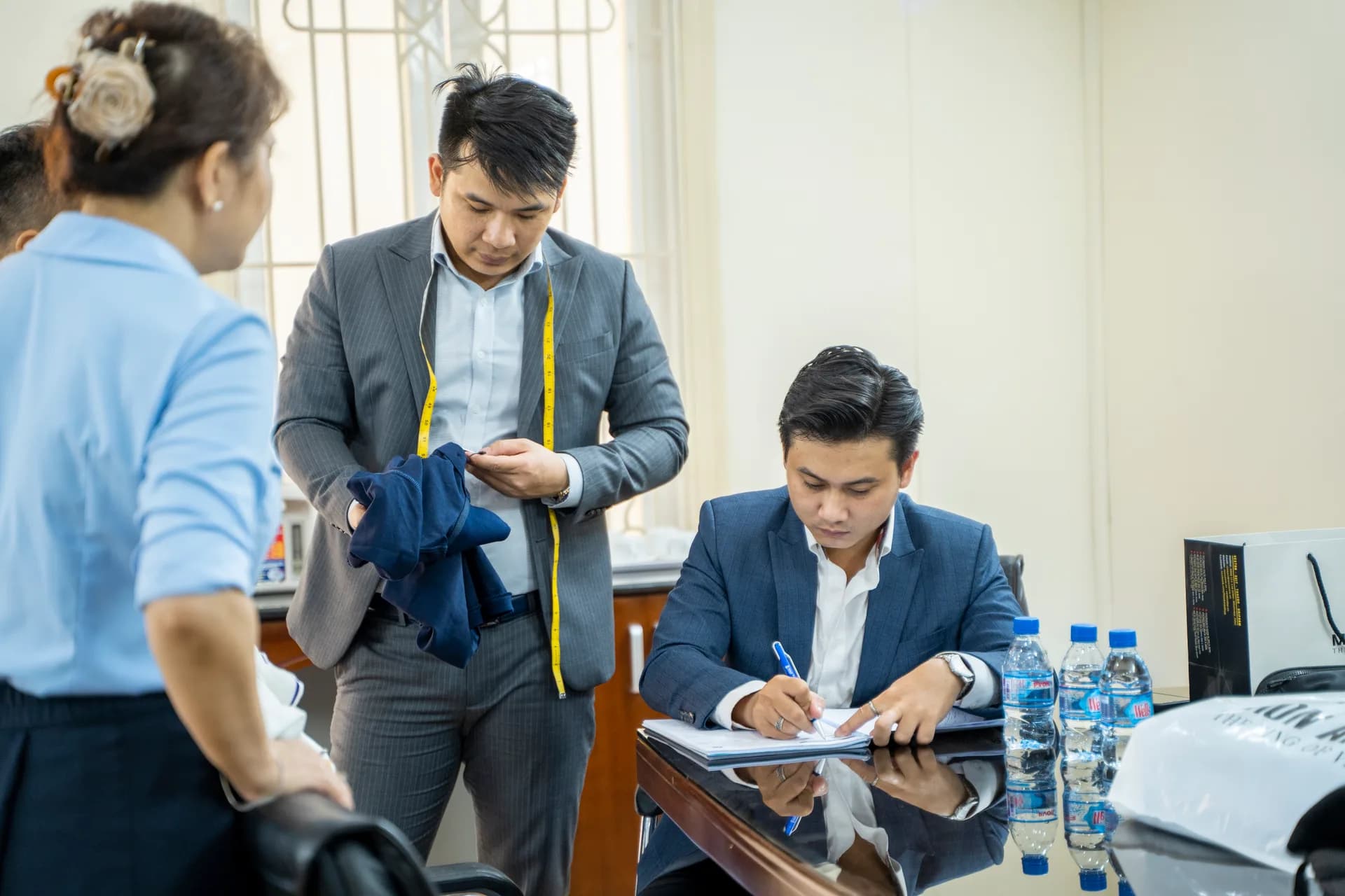 Thợ cầm áo mẫu, đồng nghiệp ghi phiếu số đo