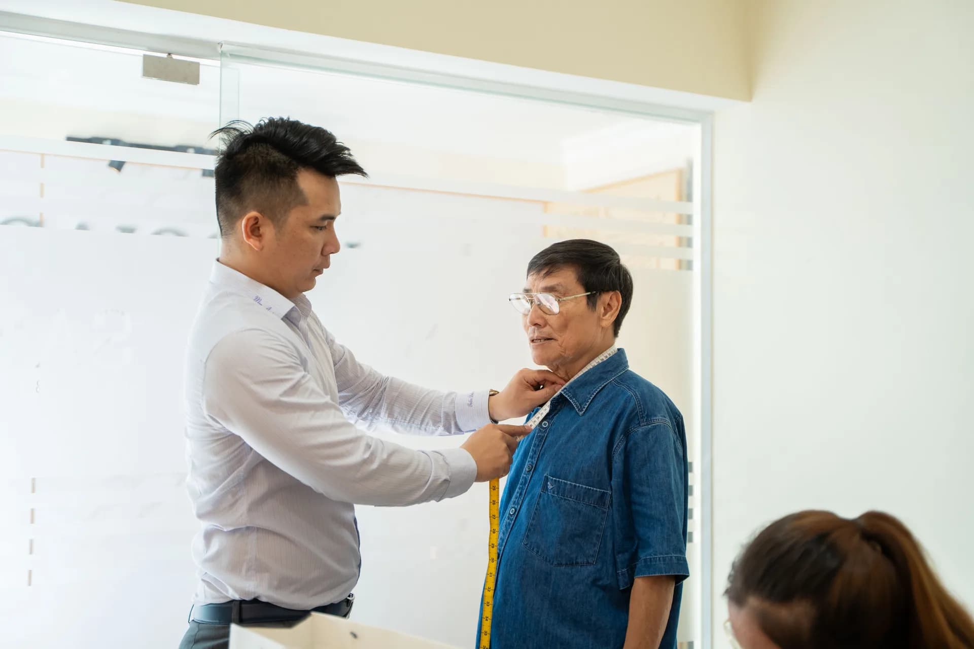 Đo vòng cổ và chiều dài áo cho nhân viên lớn tuổi