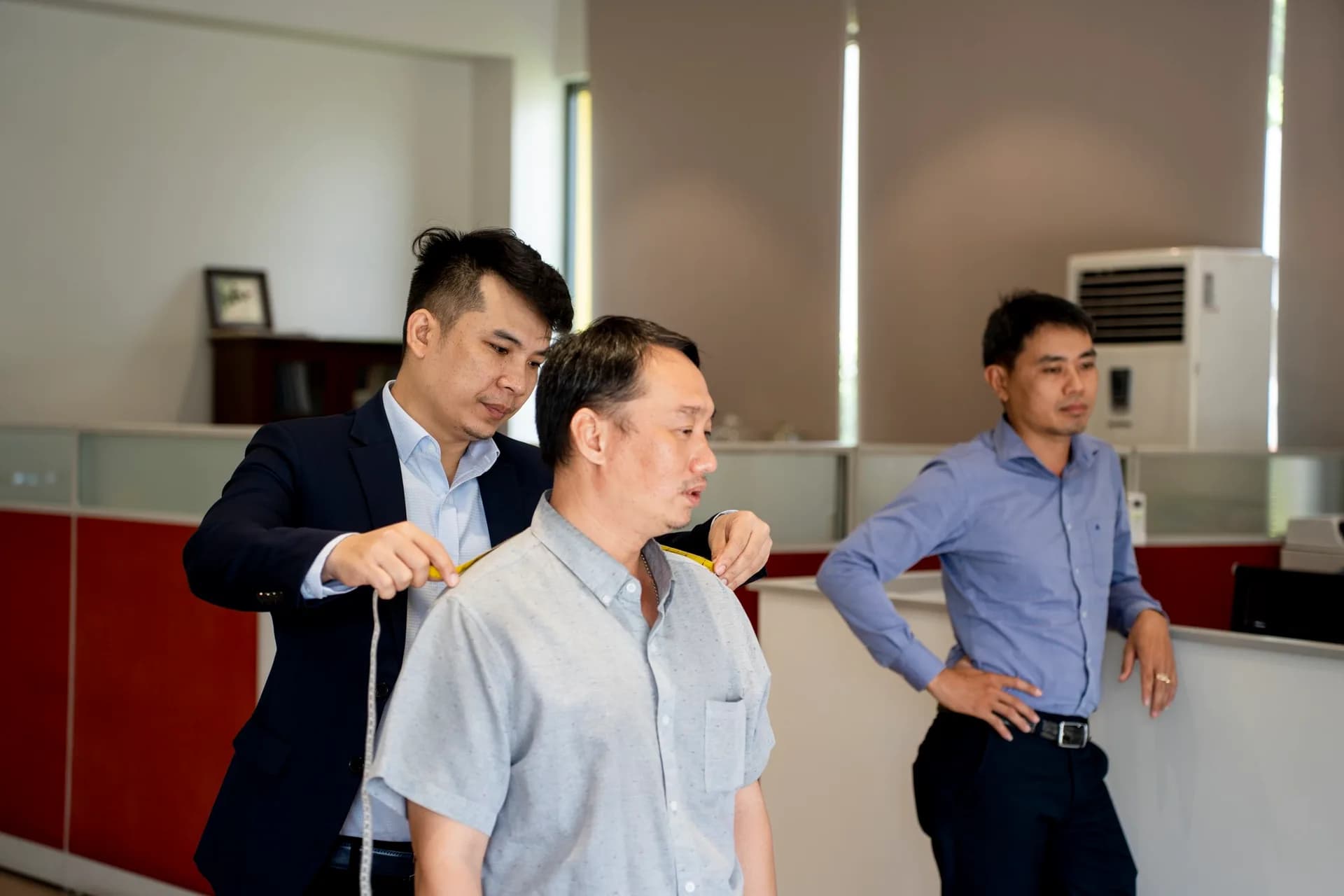 Đo vai cho nhân viên nam, đồng nghiệp chờ bên cạnh