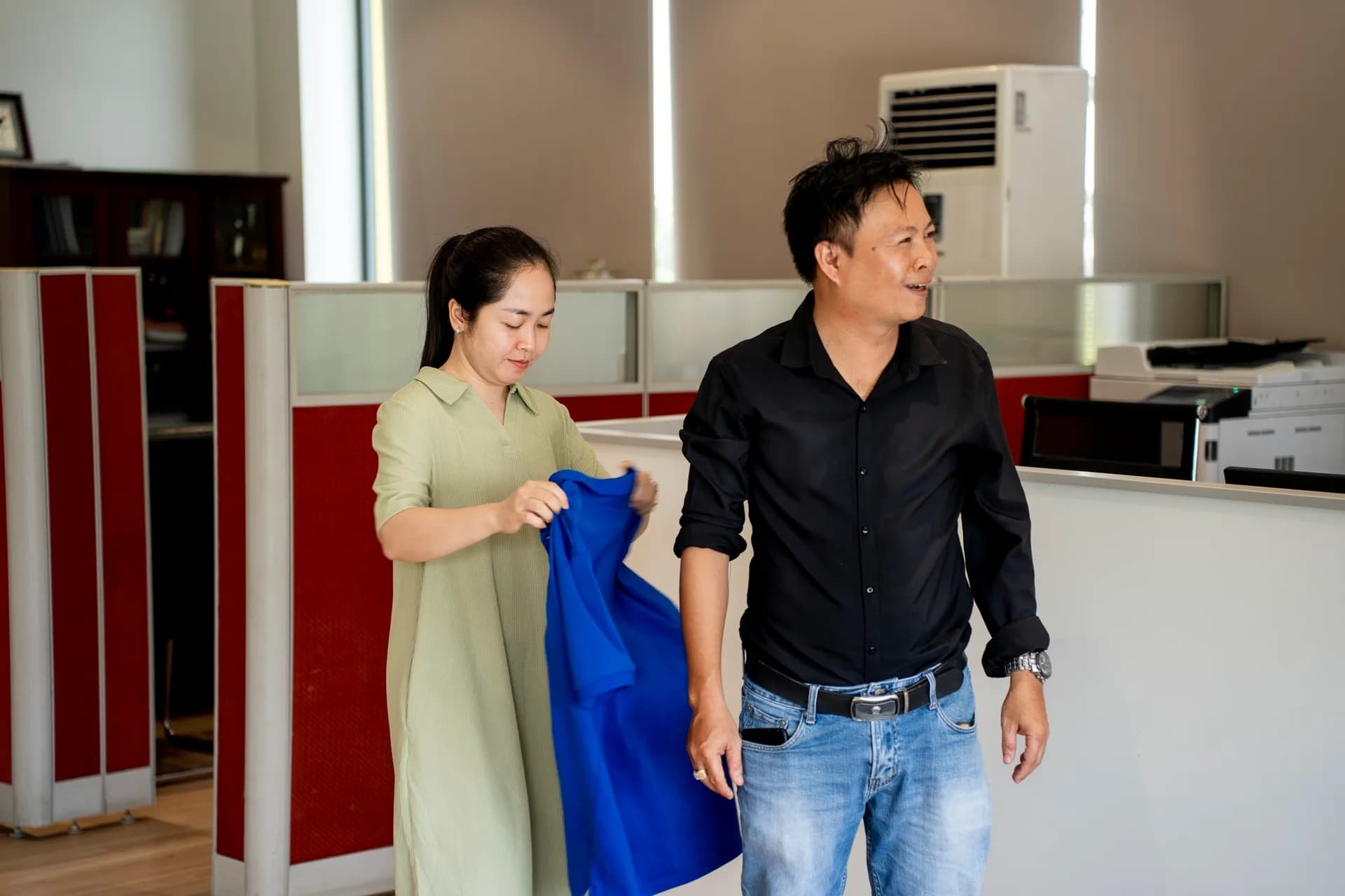 Nhân viên nữ xem áo polo xanh mẫu trước khi đo