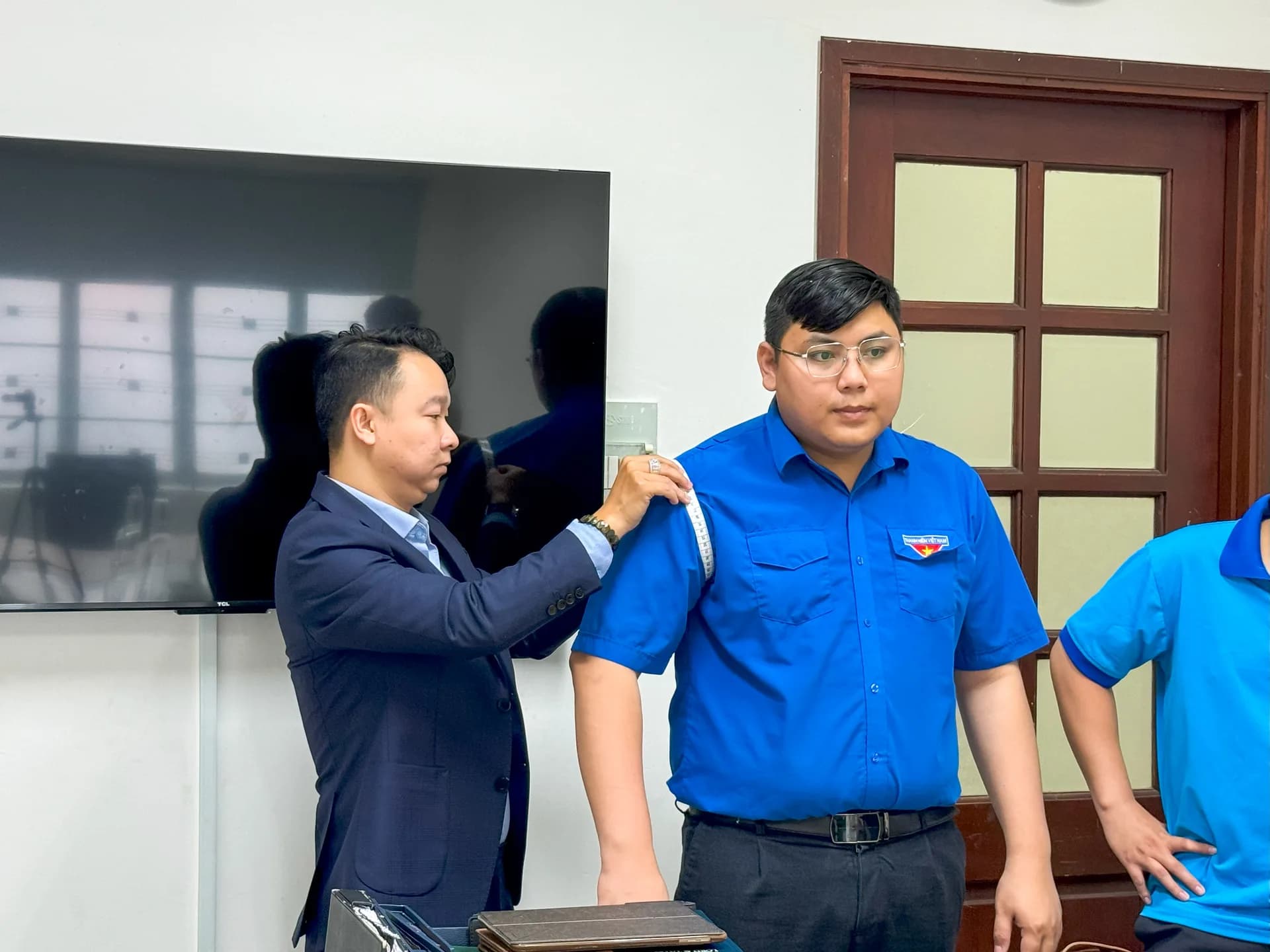 Đo vai cho cán bộ đoàn nam mặc áo thanh niên xanh