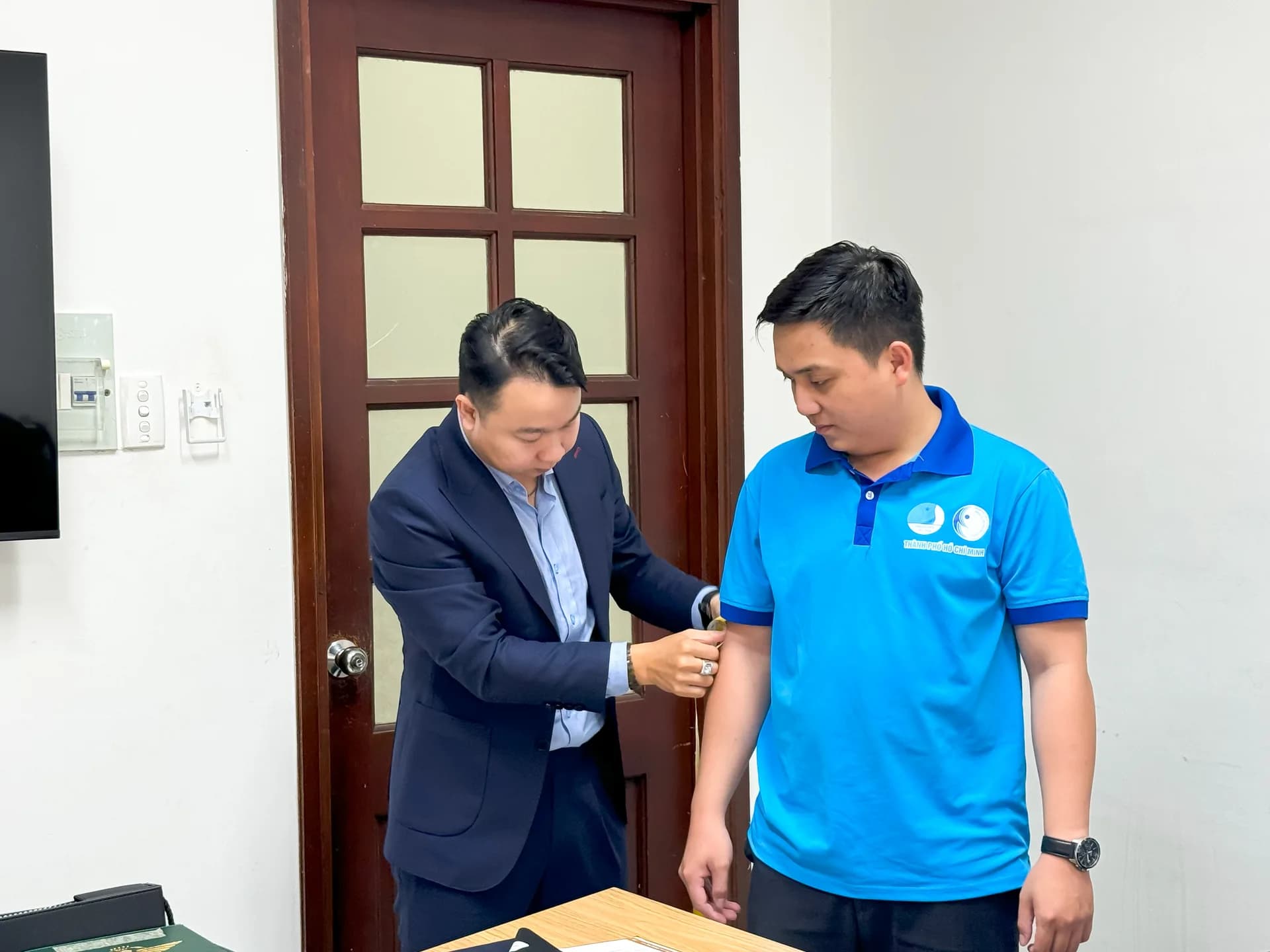 Đo tay áo cho cán bộ đoàn mặc áo polo xanh