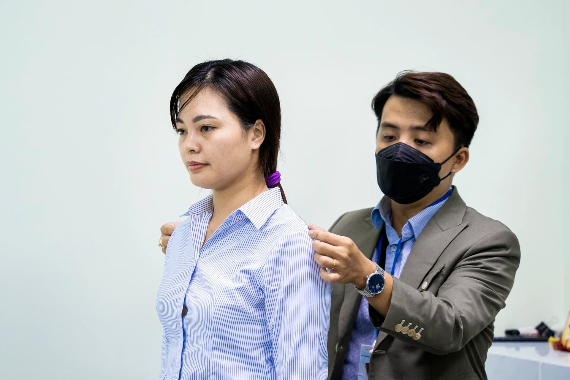 Đo vai cho nhân viên nữ mặc sơ mi kẻ sọc xanh