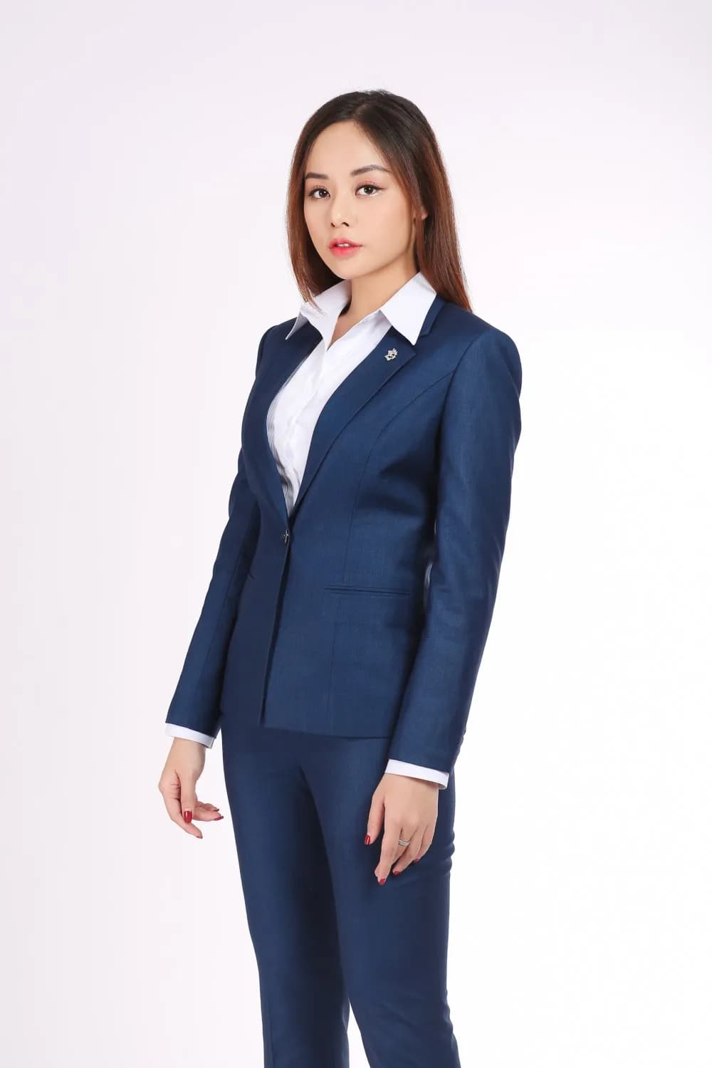 Nữ vest xanh navy kèm quần tây, sơ mi trắng, dáng nghiêng người nền sáng
