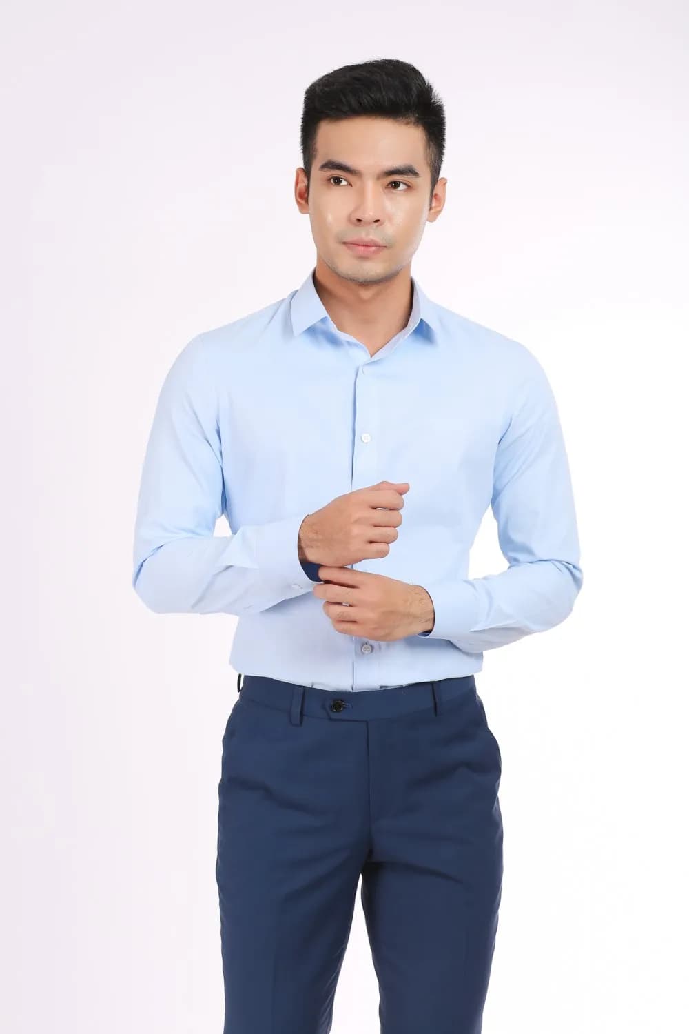 Nam sơ mi xanh nhạt, quần navy, hai tay chỉnh măng sét, nền studio sáng