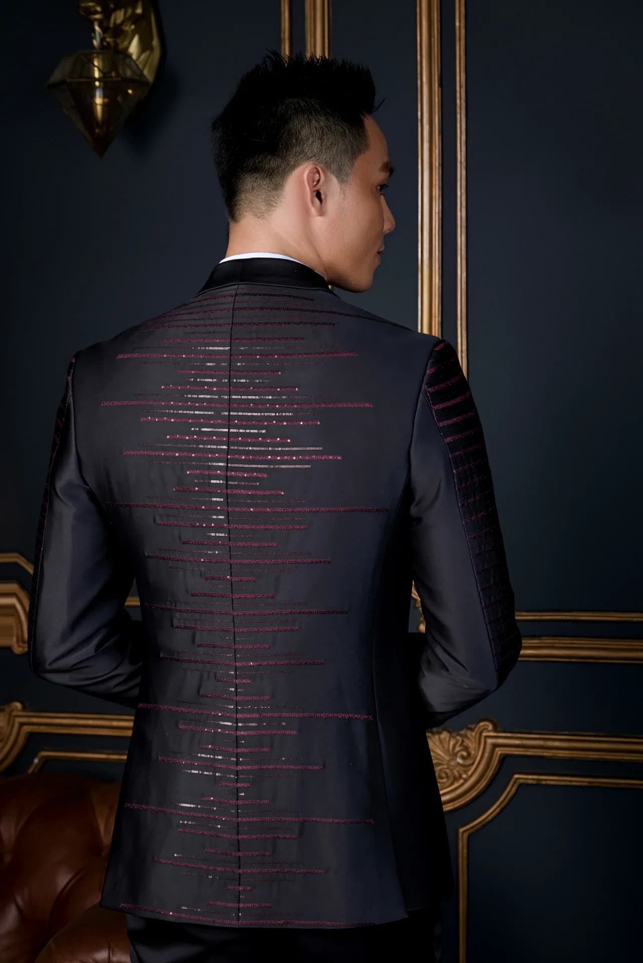 Suit đen đường viền xanh ba mảnh, nơ xanh navy, khoác măng tô nâu lạc đà.