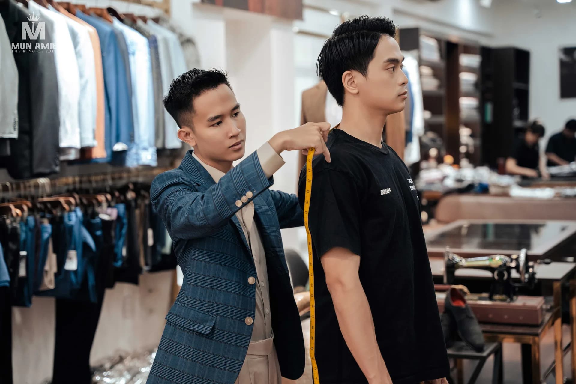 Thợ may lấy số đo vai bằng thước dây, bước đầu của bộ vest may đo và là gốc của mọi bảng size vest nam