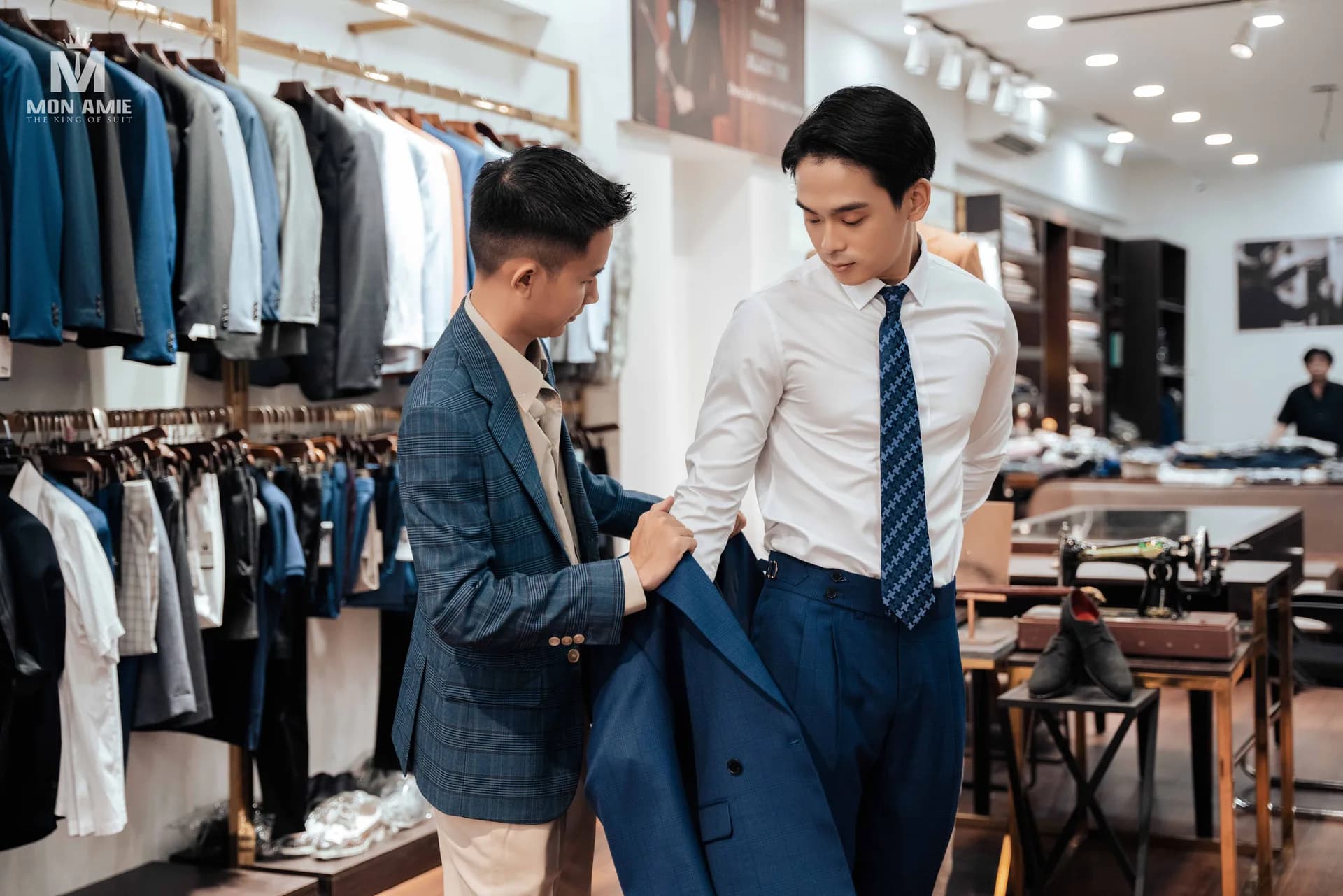 Khoác thử vest xanh navy, thợ chỉnh phom quanh vai và tay áo để kiểm tra mặc vest thế nào là vừa