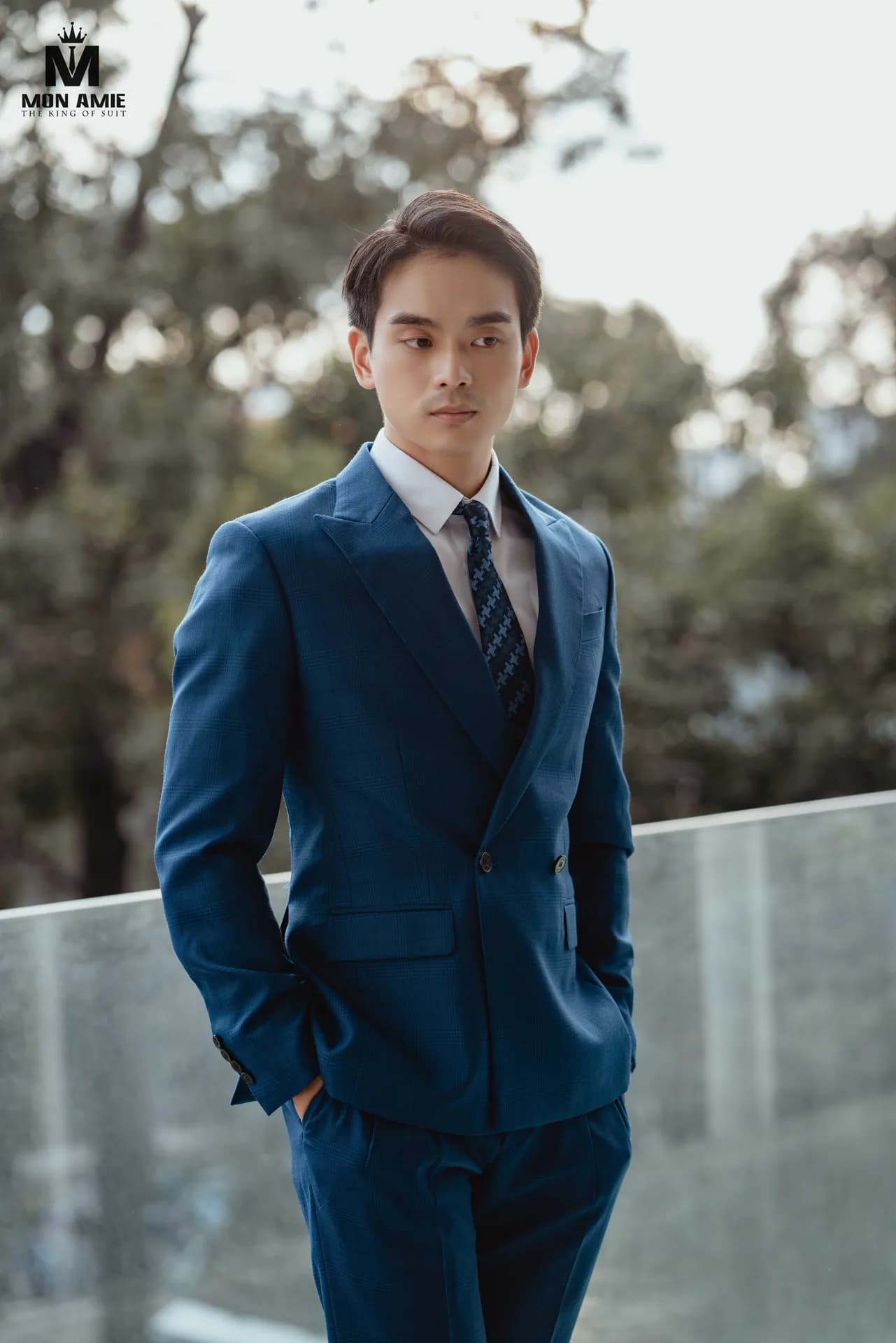 Suit hai hàng khuy xanh sapphire, cà vạt họa tiết, tay đút túi trên ban công