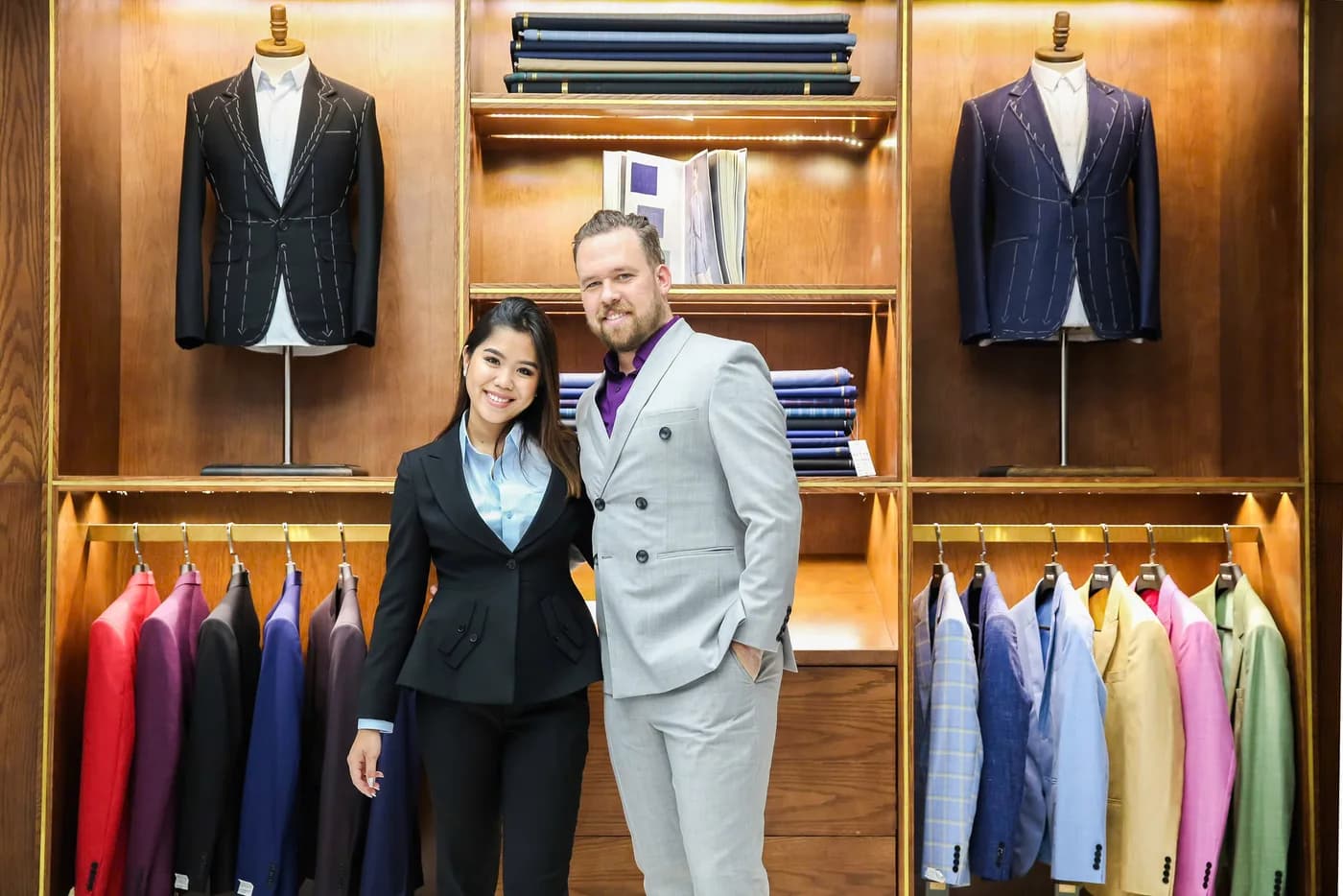 Cô gái vest đen và quý ông vest xám nhạt đứng cạnh nhau, minh họa chọn thuê vest hay may vest theo số lần mặc