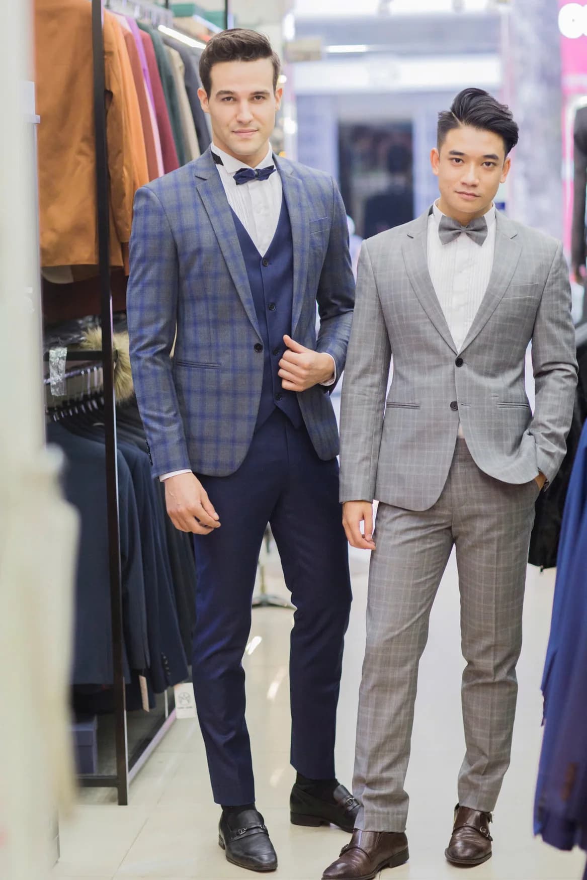 Hai chàng trai vest caro xanh và vest xám, thắt nơ