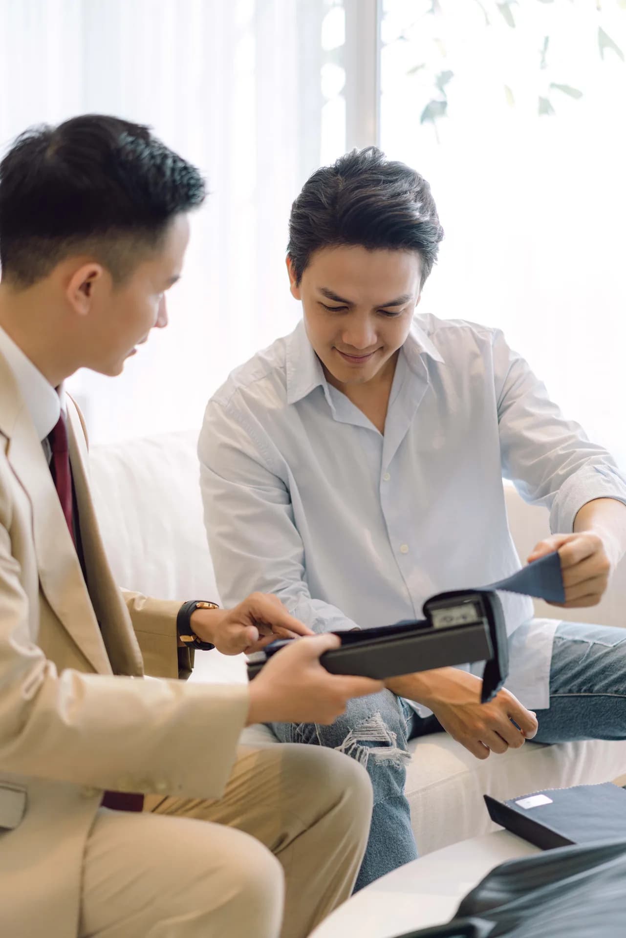 Khách mỉm cười cầm mẫu vải, nghệ nhân tư vấn ngay bên cạnh, bước chọn vải quyết định phần lớn giá may vest
