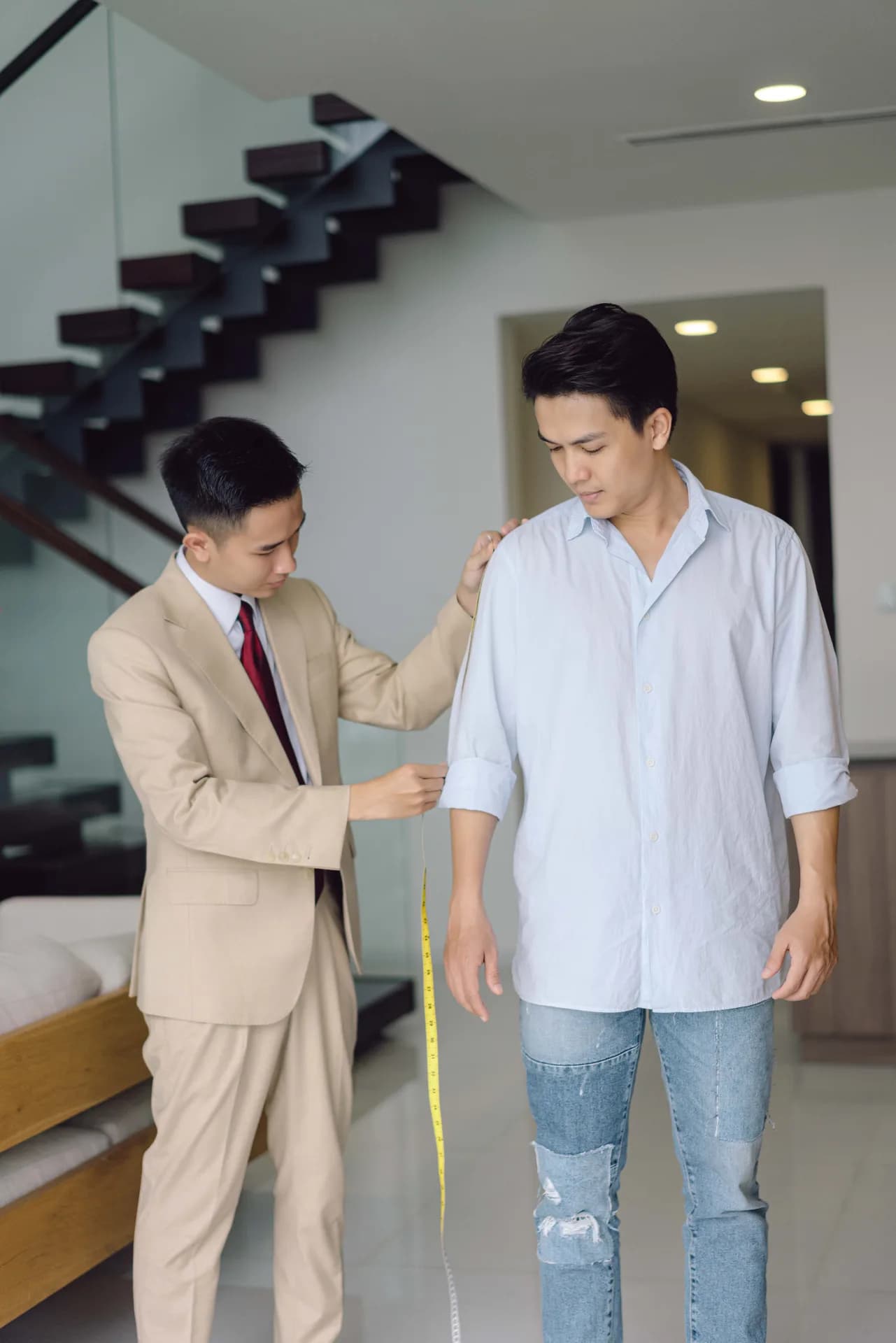 Đo tay áo trong ánh sáng dịu, thước dây vàng buông dọc thân