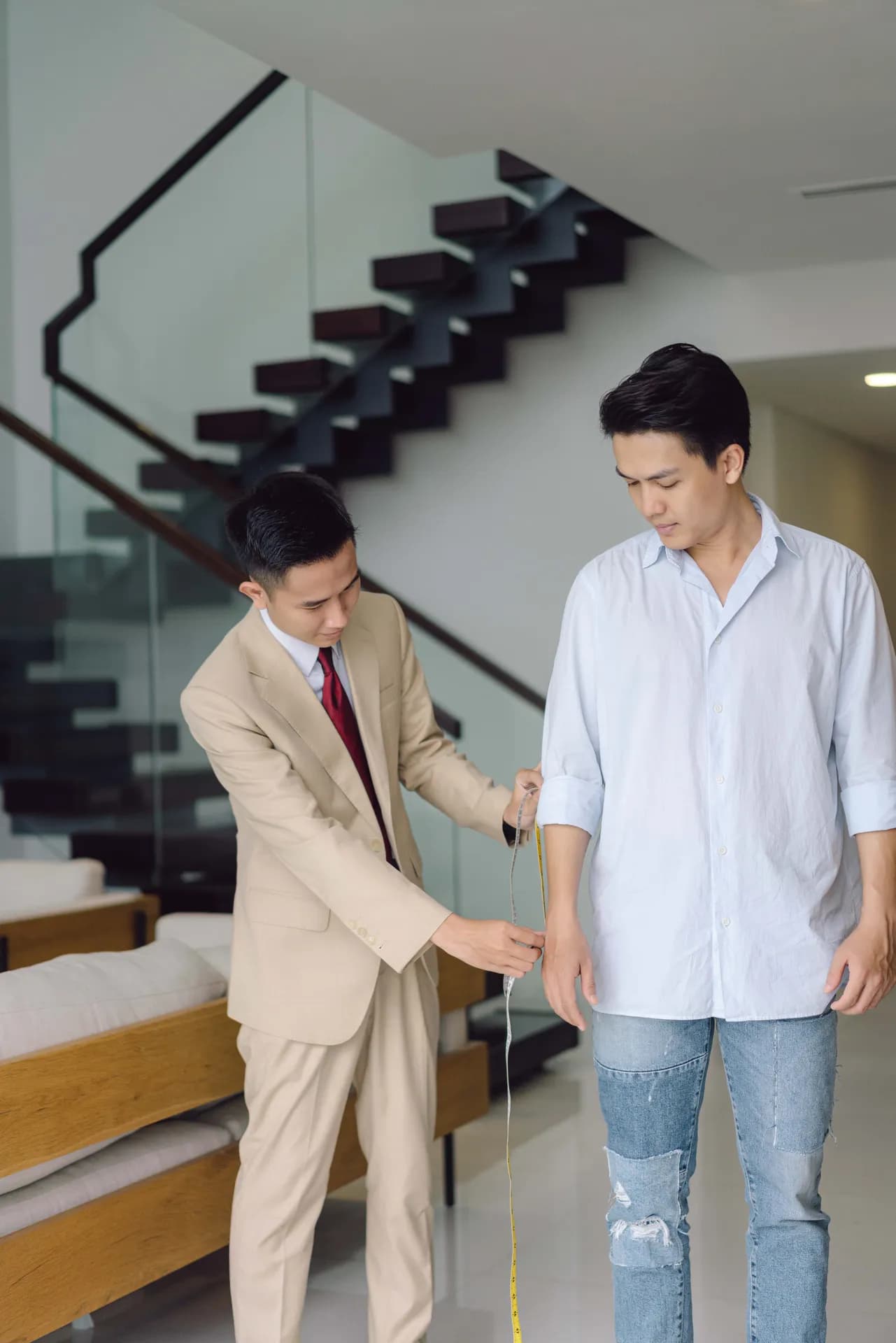Đo dài tay cho khách bằng thước dây bên cầu thang kính