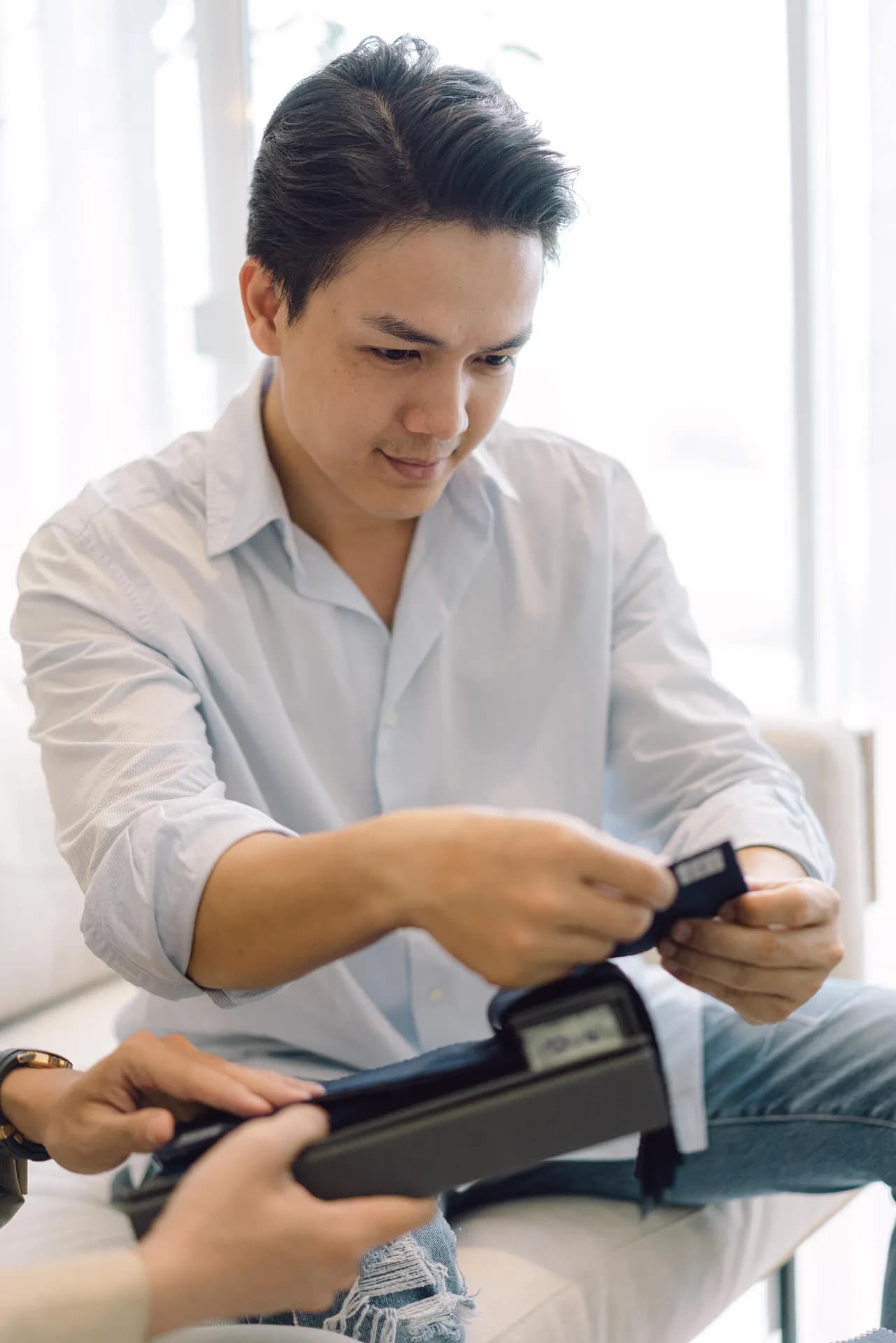 Khách cười tươi cầm sổ mẫu vải trong buổi tư vấn may đo tận nơi