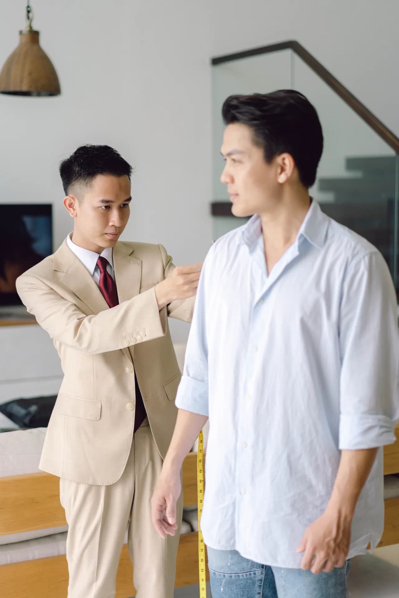 Thợ may đo vai và thân áo cho khách đứng thẳng, vest màu be