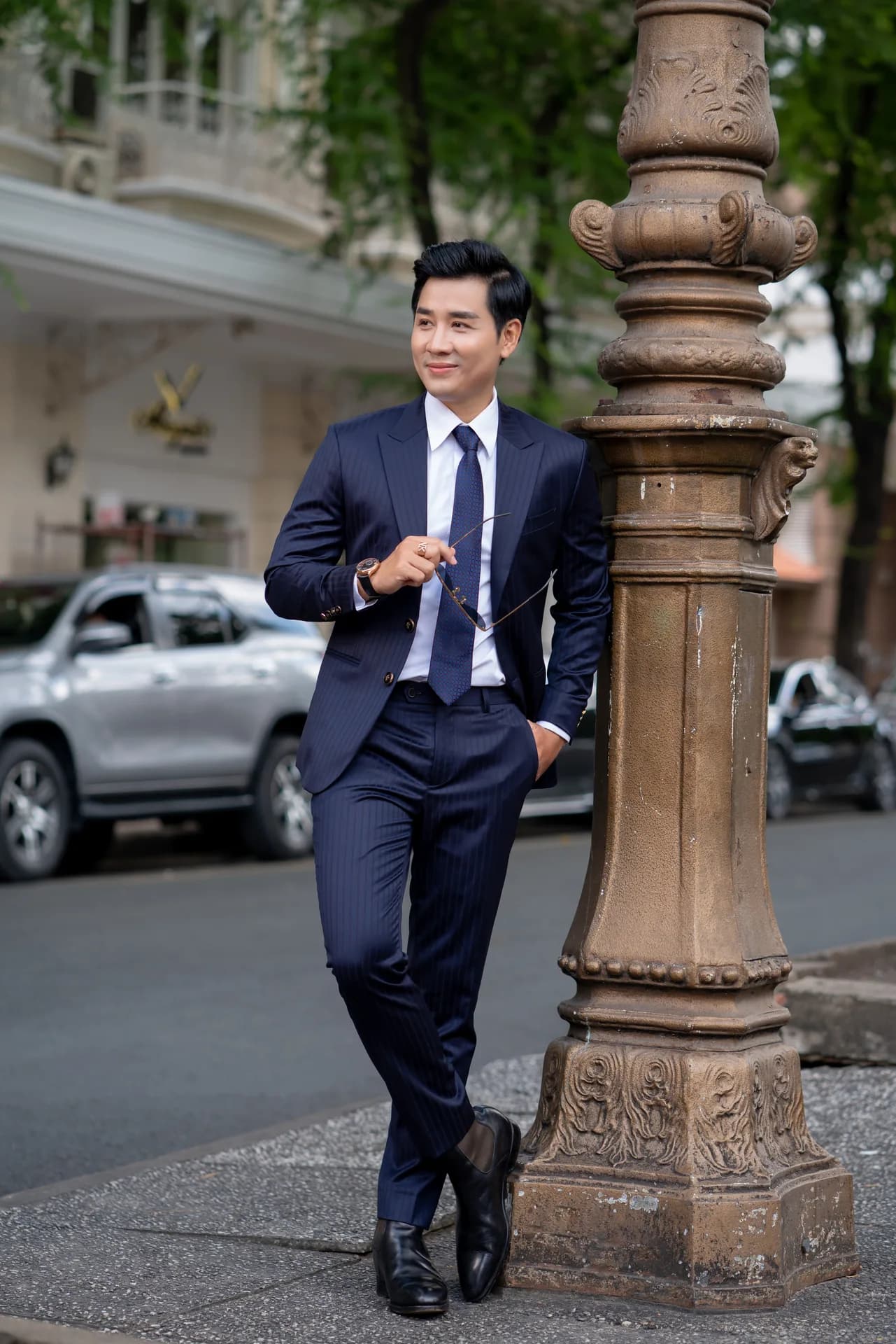 Suit xanh navy kẻ sọc, sơ mi trắng, tựa cột đèn đồng cổ, gợi ý đám cưới mặc vest màu gì