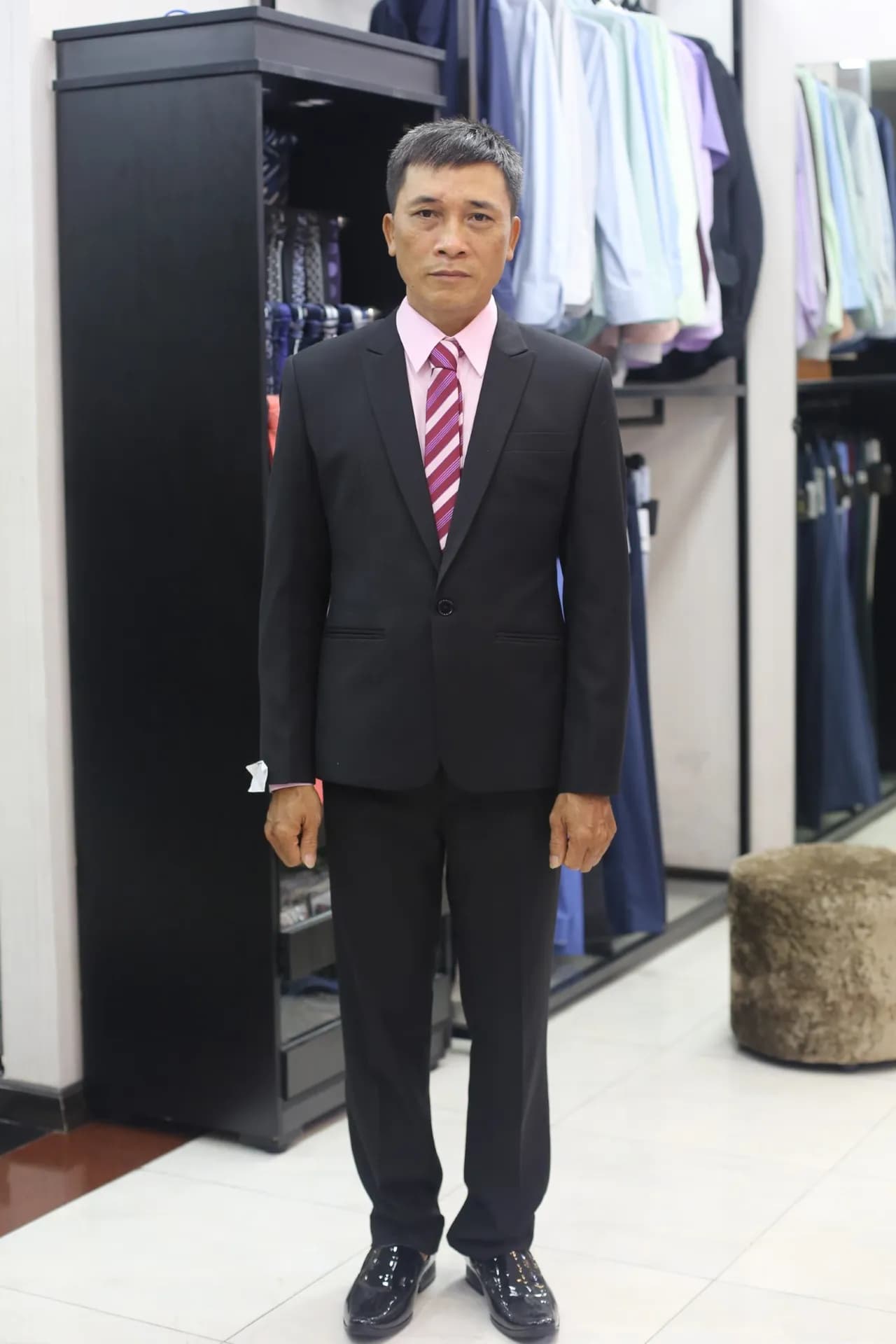 Suit đen một cúc, sơ mi hồng phấn, cà vạt sọc tím đỏ