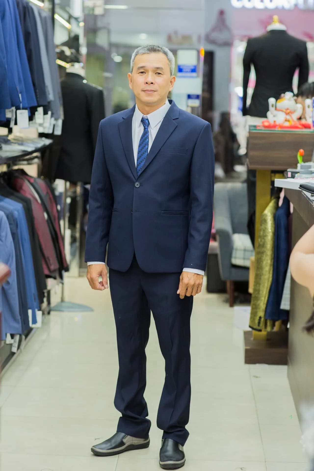 Suit navy hai cúc, cà vạt xanh họa tiết, dáng đứng thẳng chỉnh tề