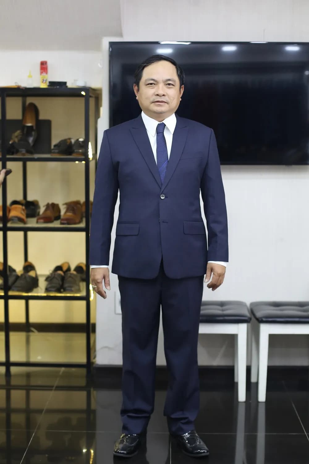 Suit xanh navy cà vạt xanh trên nền tường sáng, gọn gàng chỉnh tề
