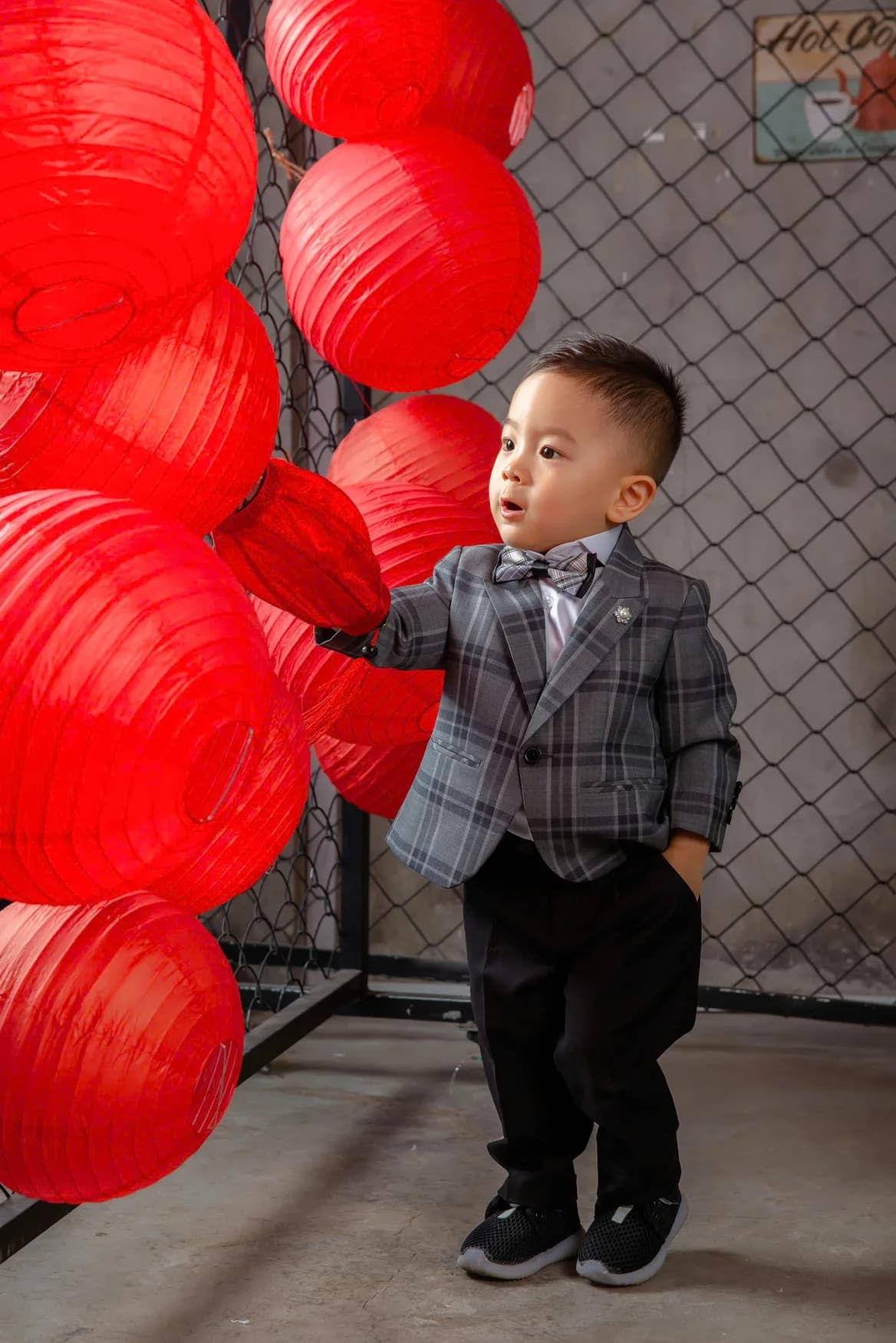 Bé trai vest caro xám chạm lồng đèn đỏ, biểu cảm ngộ nghĩnh