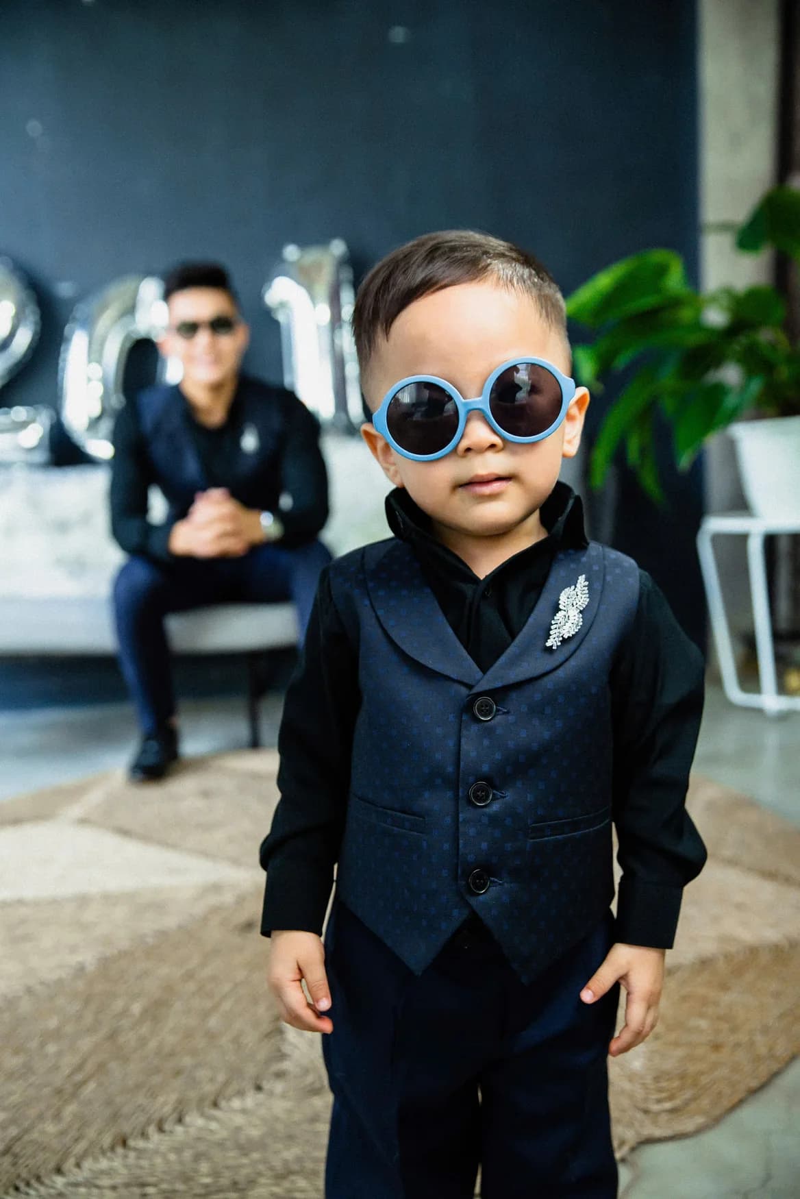 Cận cảnh bé gile navy chấm bi, kính tròn xanh, ghim cài