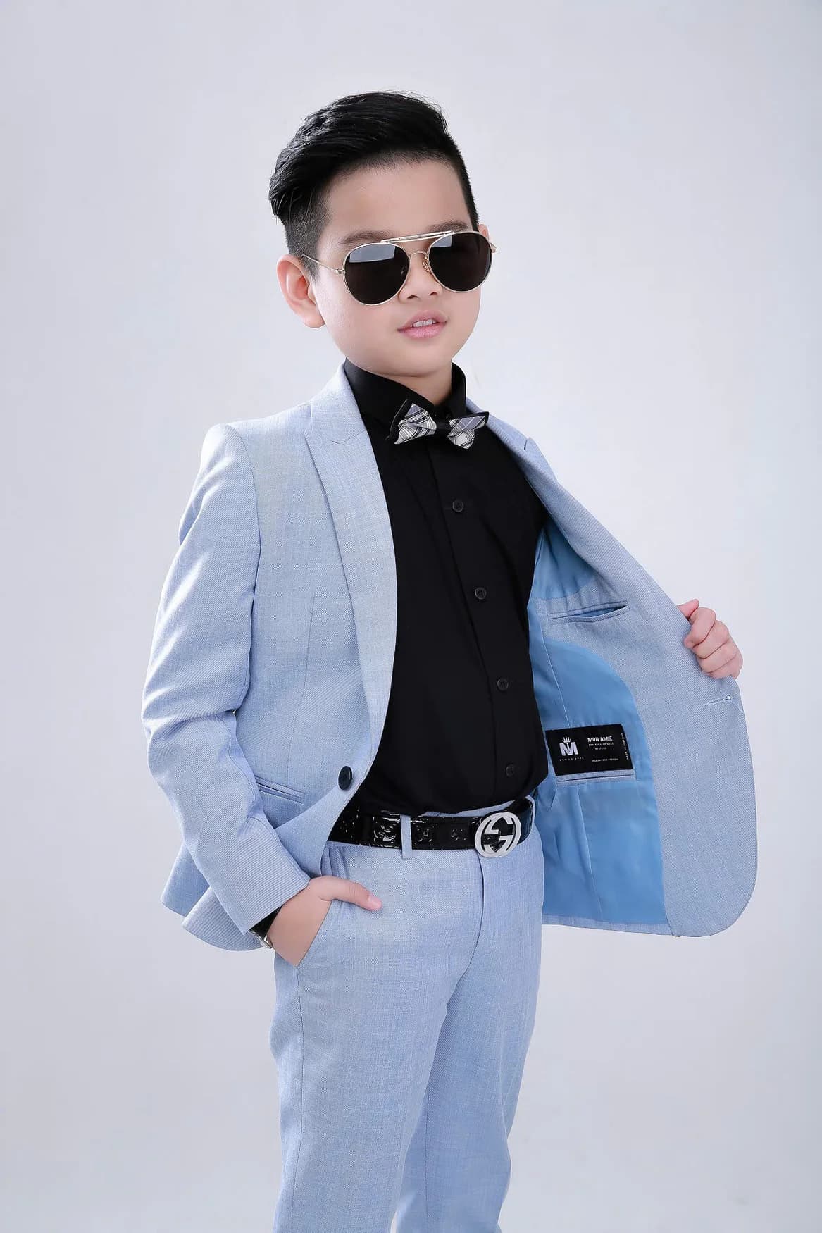 Bé trai mở vạt vest xanh pastel khoe lót, sơ mi đen
