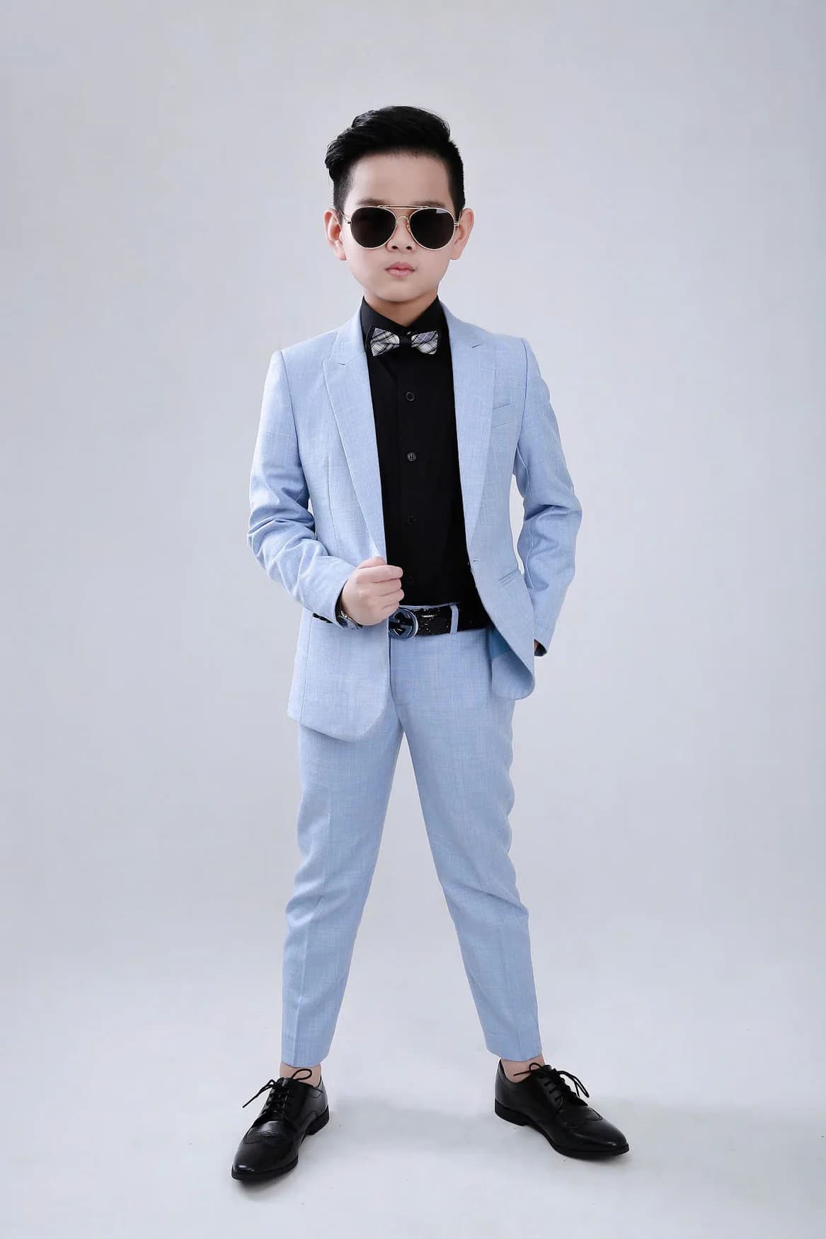 Bé trai vest xanh pastel toàn thân, kính râm, nền trắng