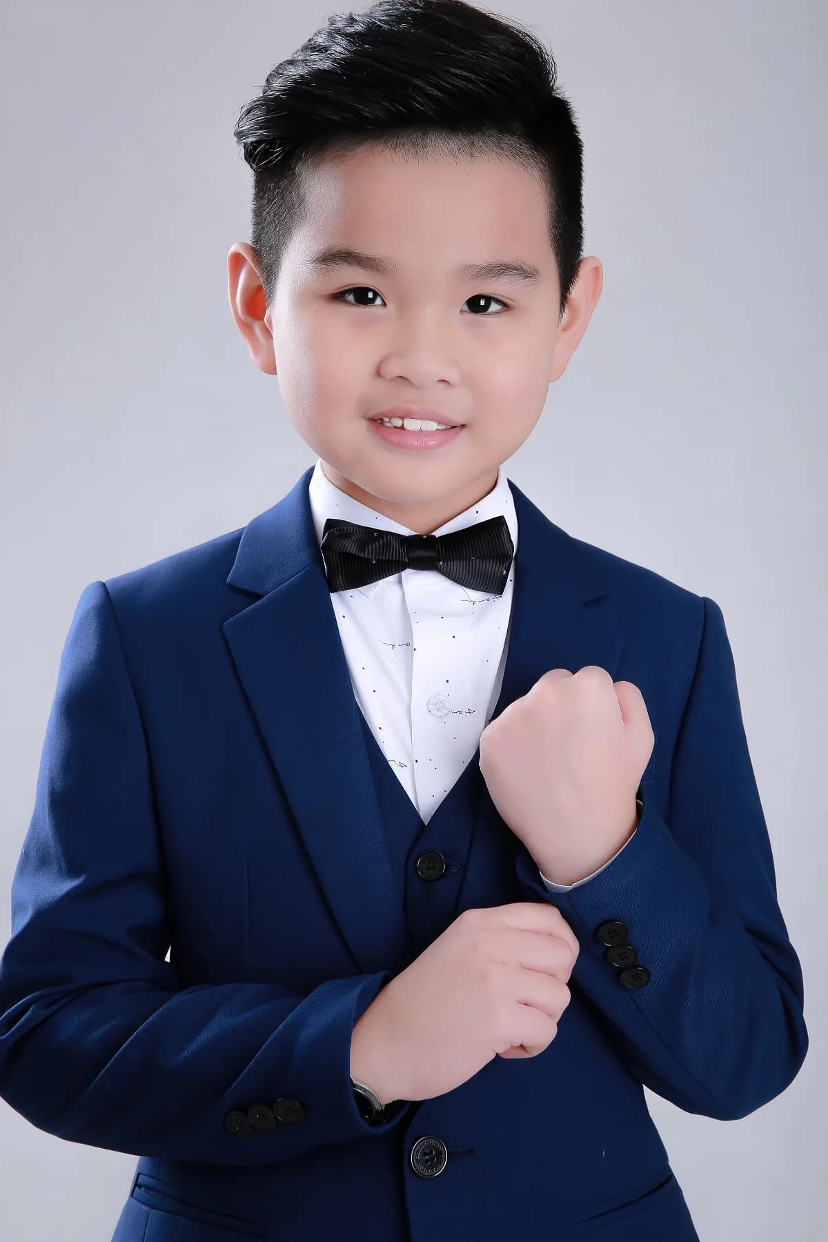 Chân dung bé chỉnh cúc tay áo vest navy, ánh mắt tự tin