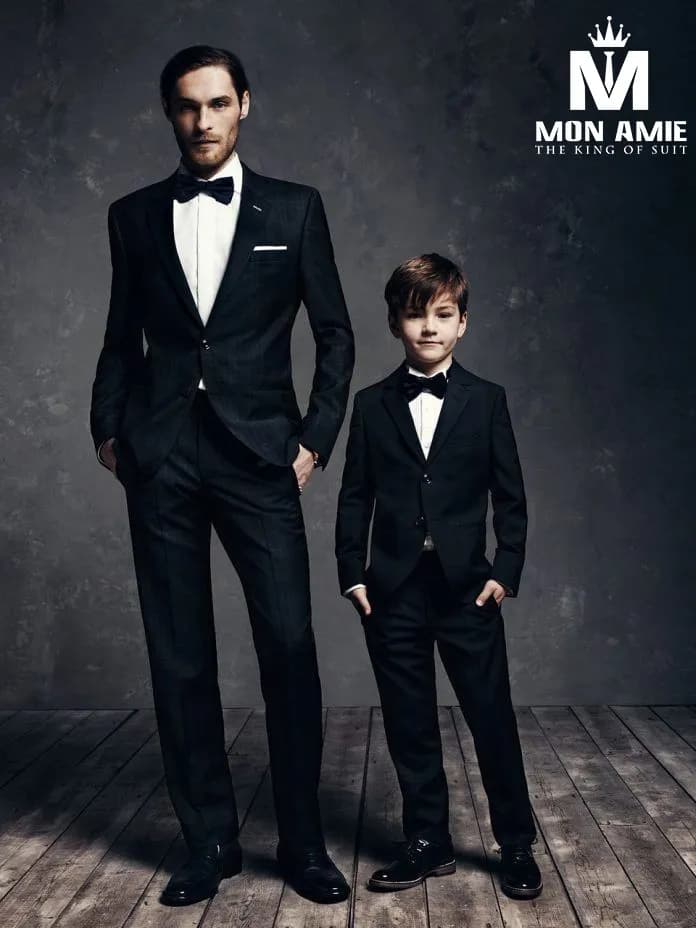 Người cao, bé thấp – hai bộ suit đen sánh đôi trên sàn gỗ nền xám