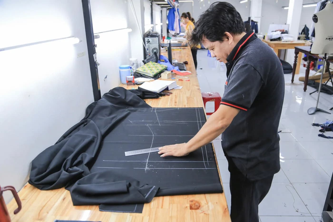 Nghệ nhân áo polo đen dùng thước kẻ rập trên vải đen