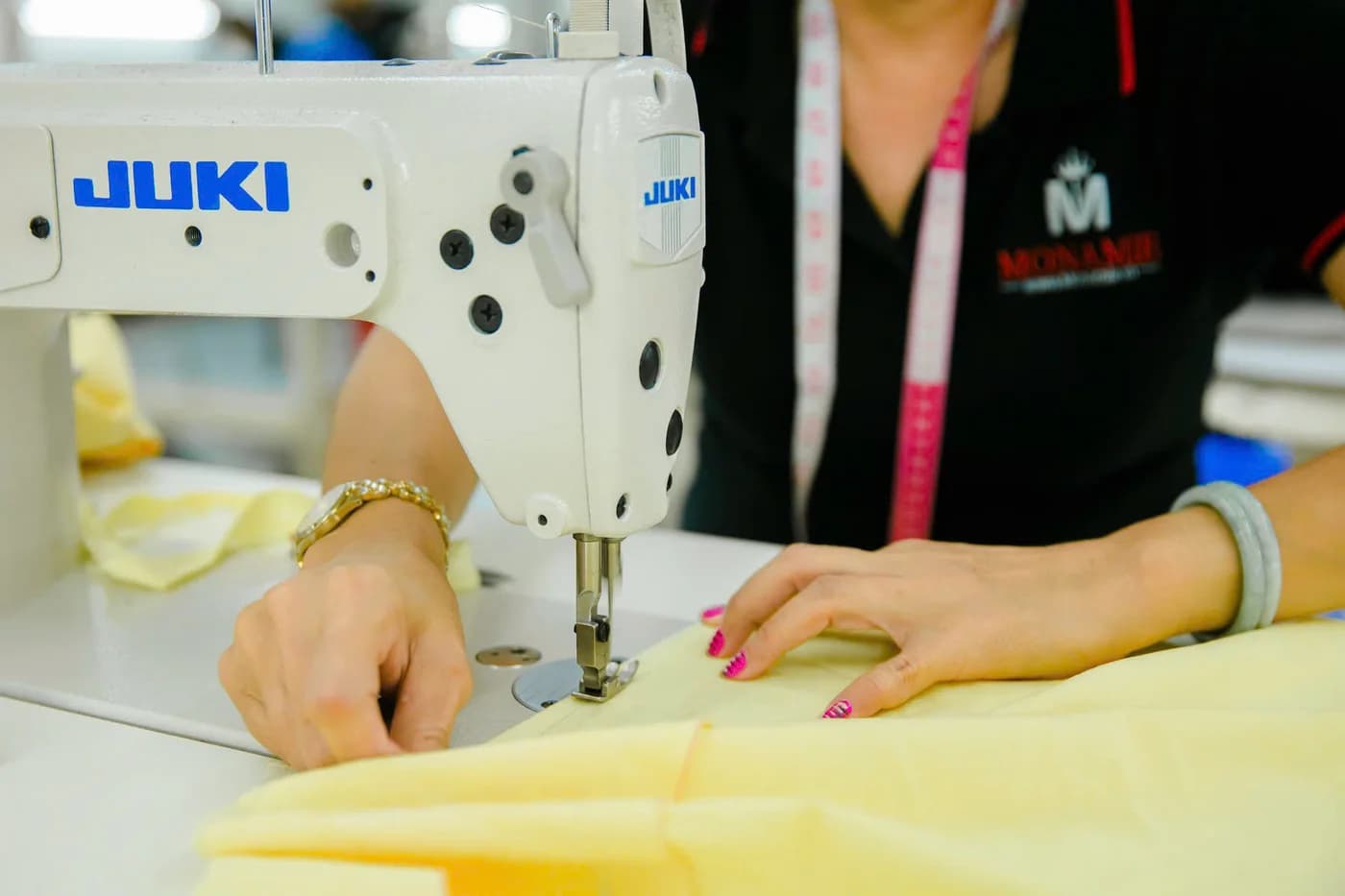 Nữ thợ áo đen may lót vàng nhạt trên máy Juki