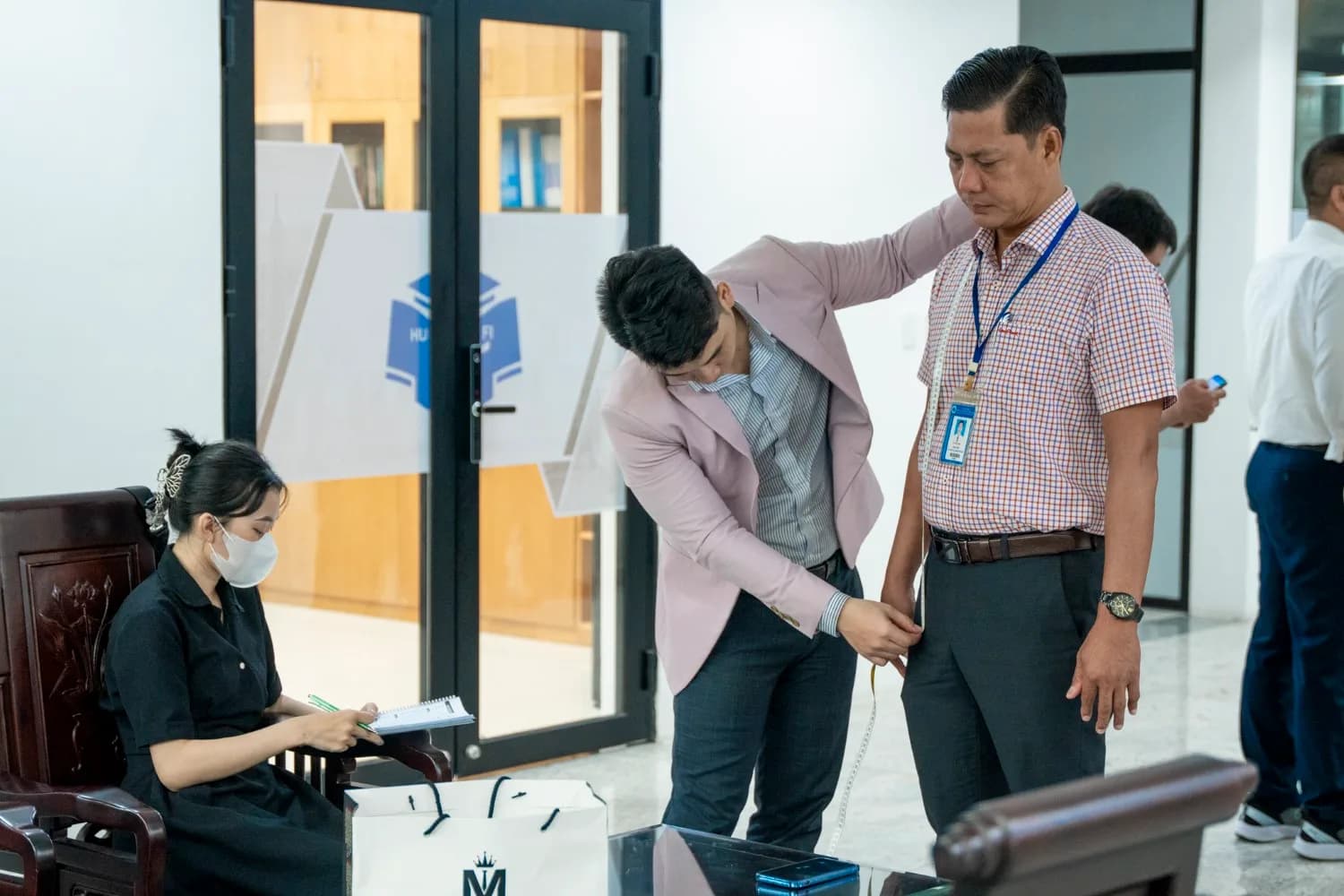 Đo vòng eo cho cán bộ trường đeo thẻ, nhân viên ghi chép số đo