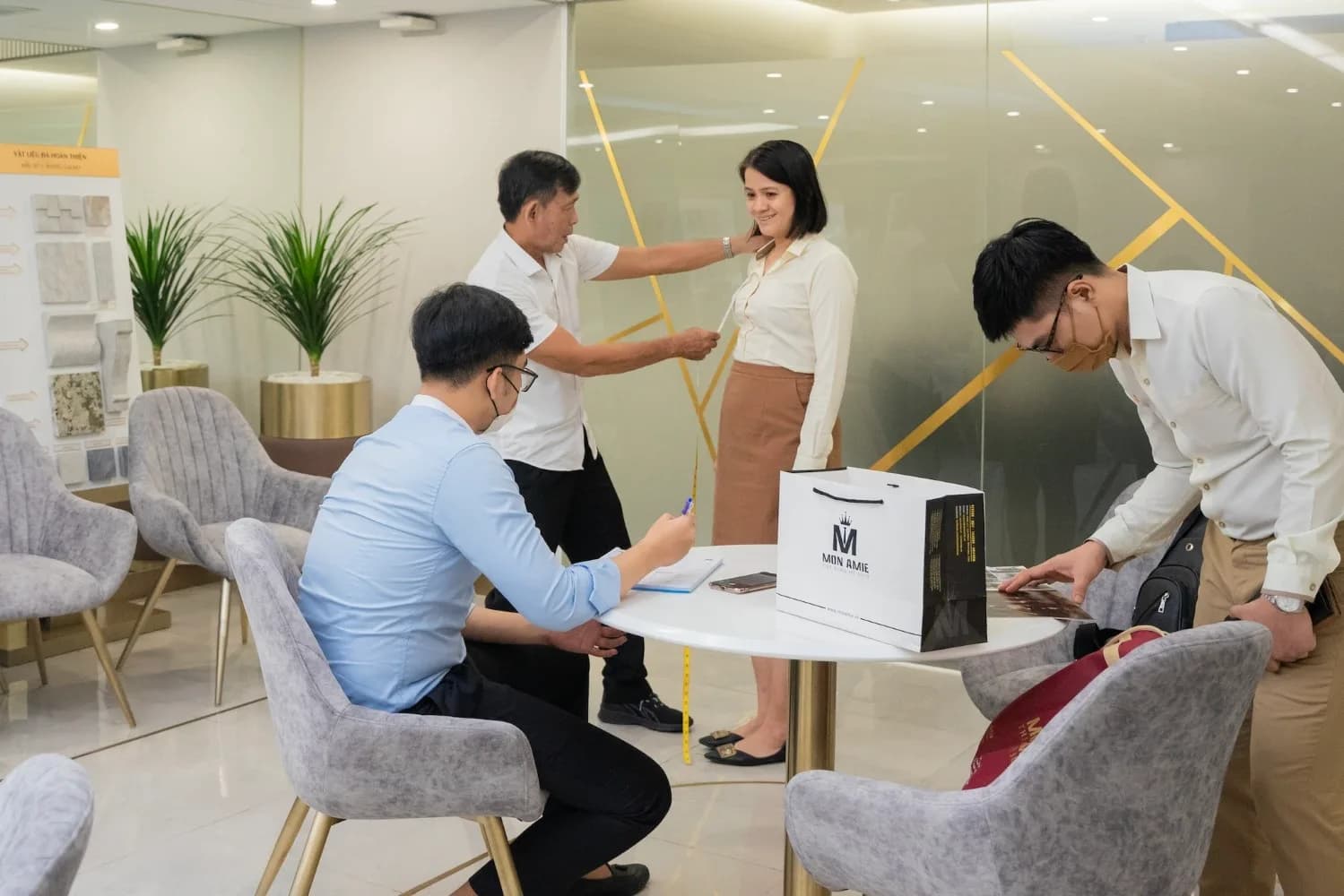 Đo vai cho nhân viên nữ, đồng nghiệp xem lookbook bên bàn tư vấn