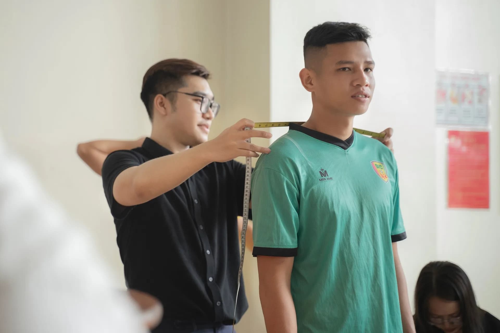 Đo ngang vai cho cầu thủ trong áo đấu xanh ngọc