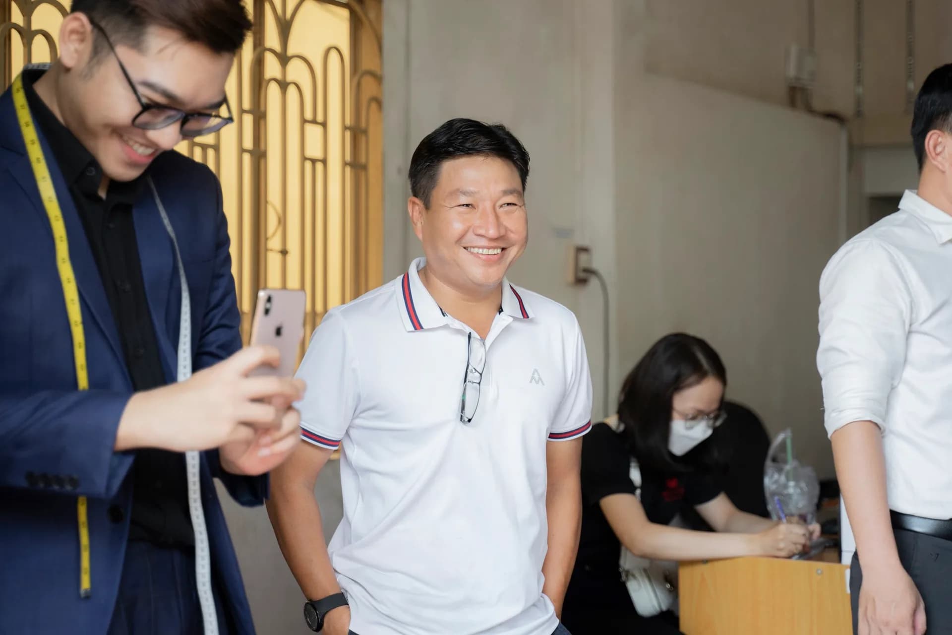 Khách cười tươi khi thợ chuẩn bị đo số đo